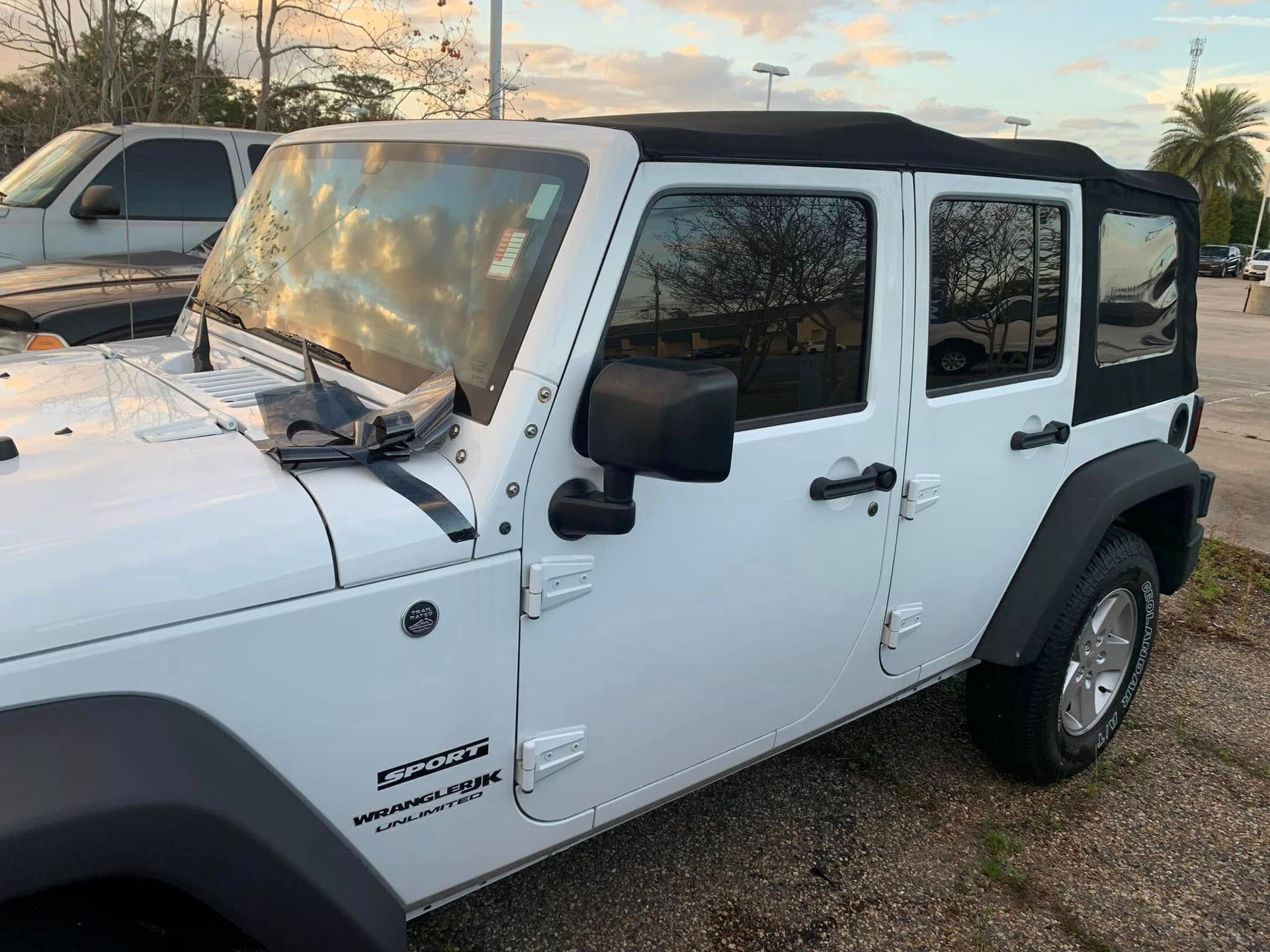 A white jeep with a black top is parked in a parking lot.