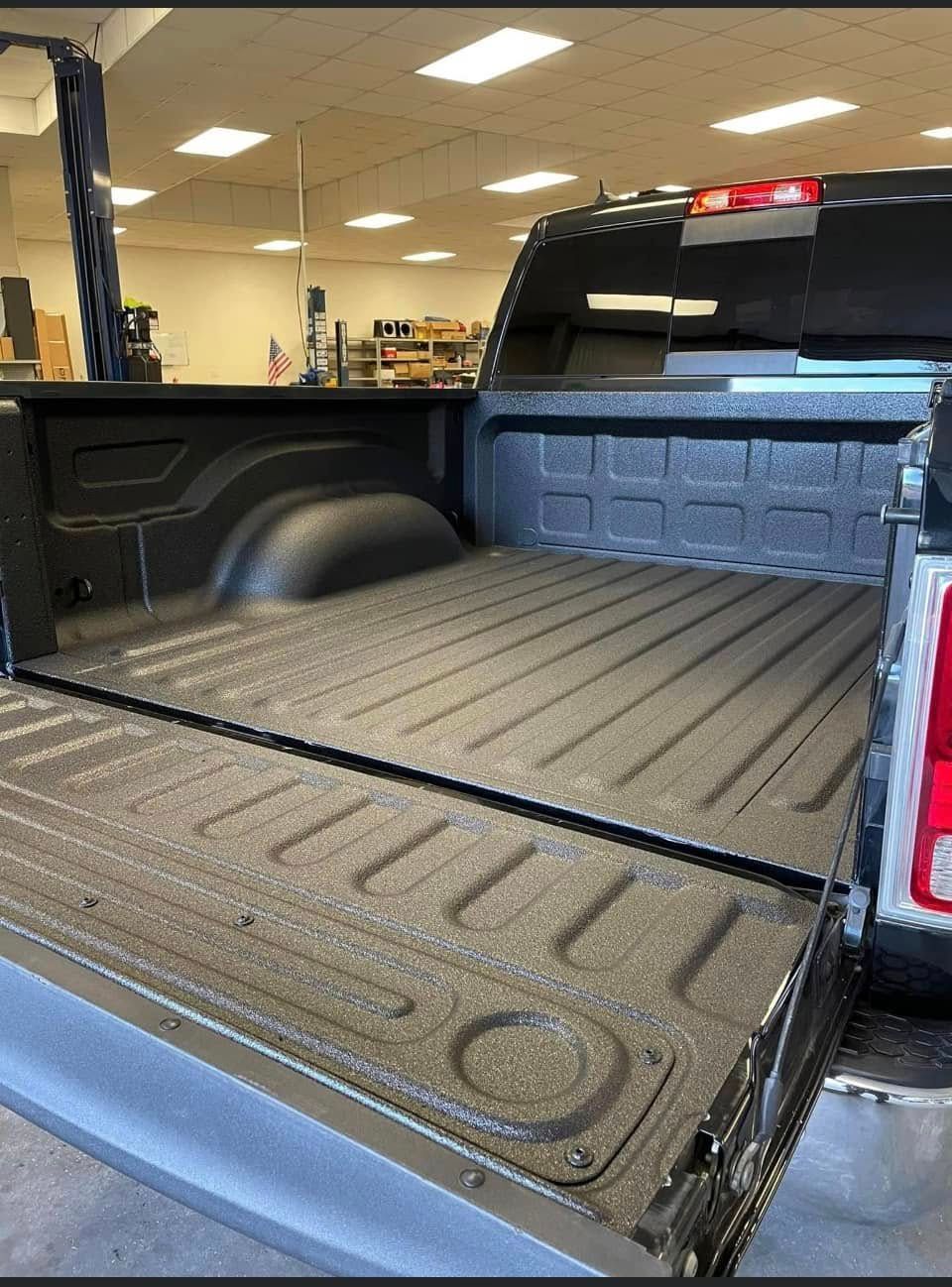 A truck is parked in a garage with the bed open.