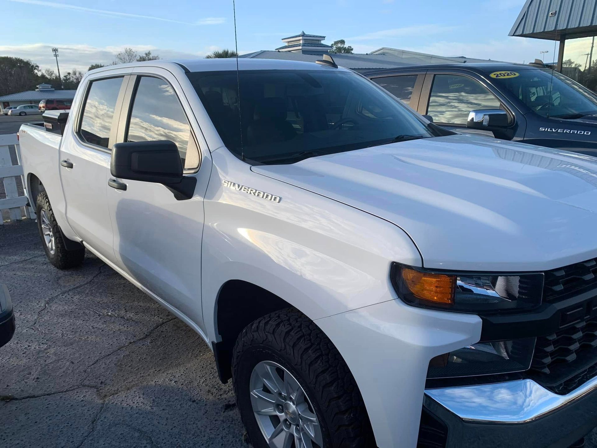 A white pickup truck is parked in front of a building.