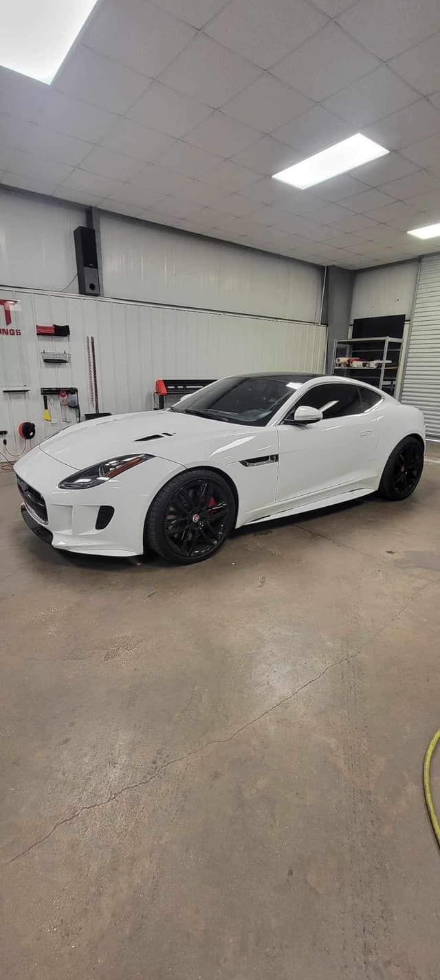 A white sports car is parked in a garage.