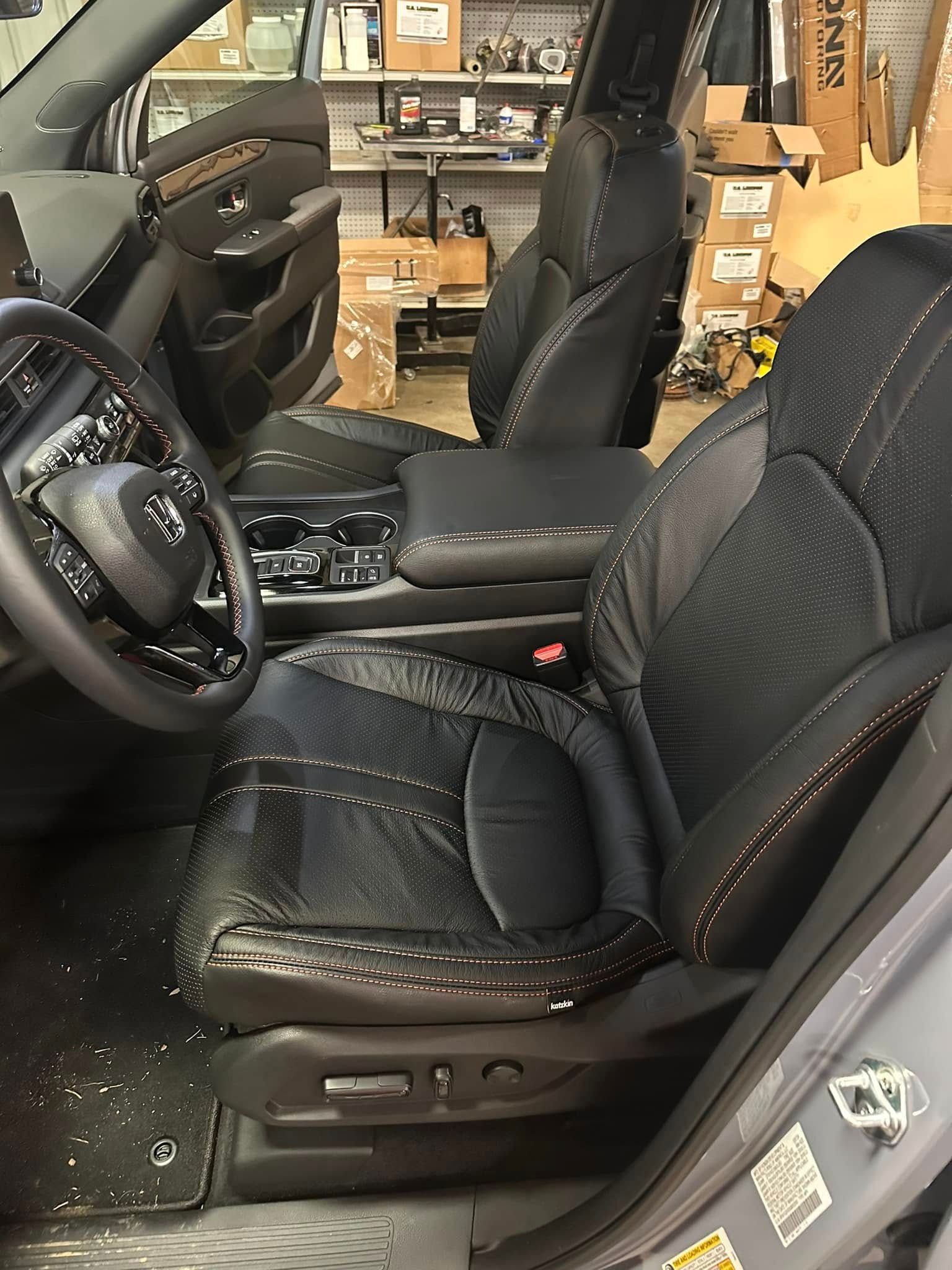 The interior of a car with black seats and a steering wheel.