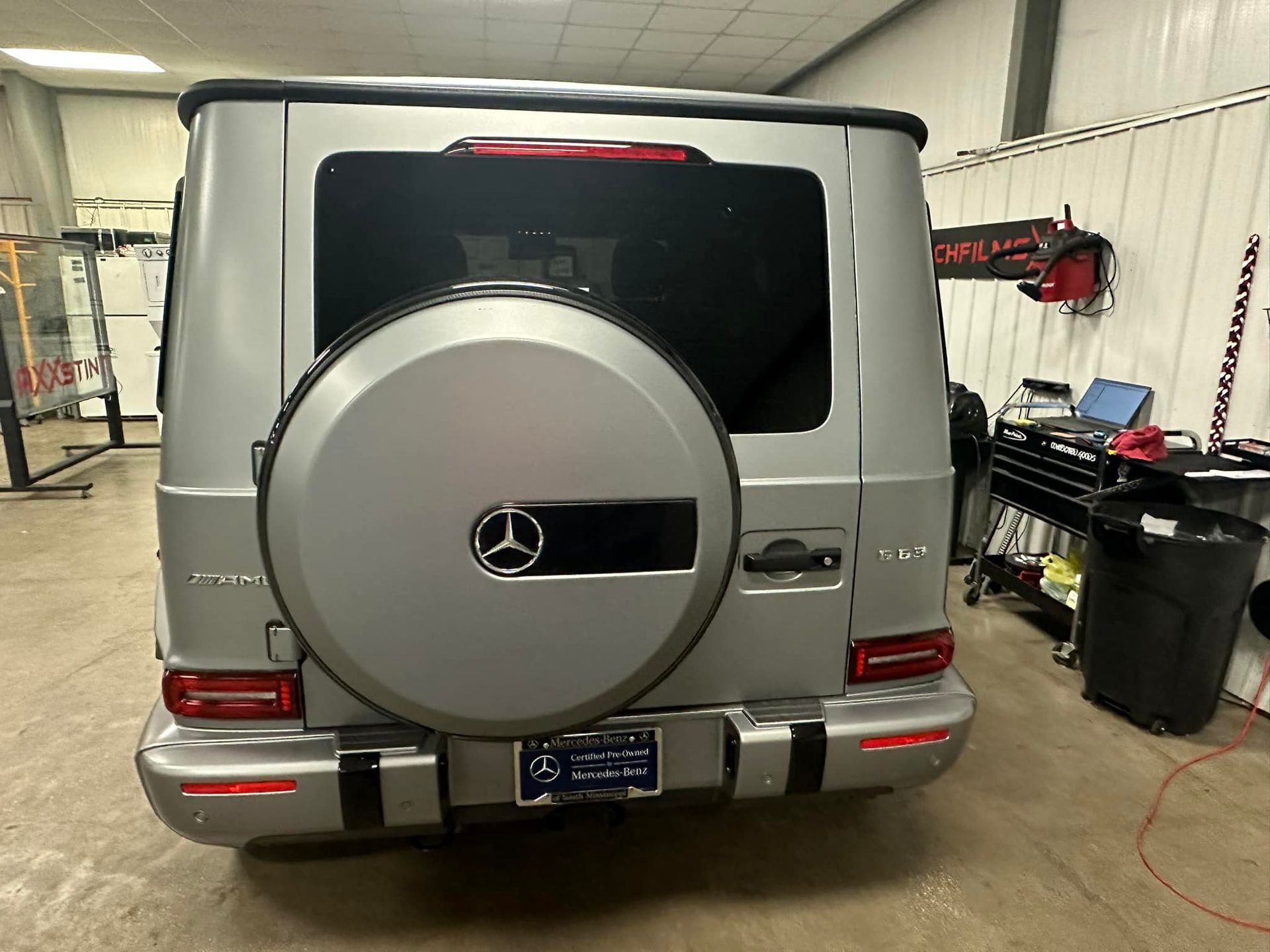 A silver mercedes benz g63 is parked in a garage.