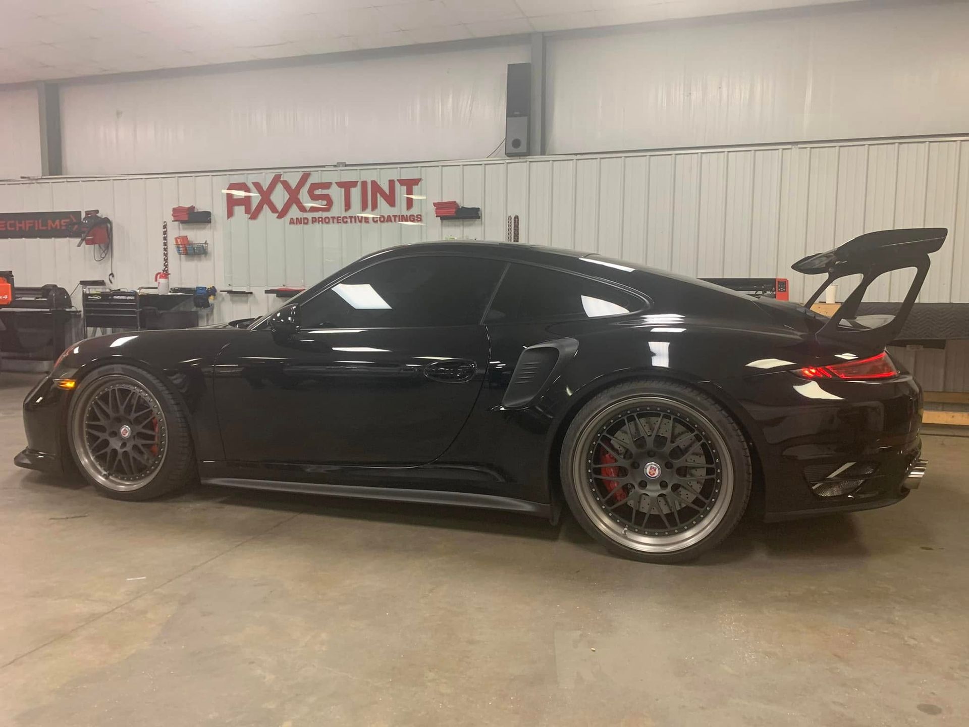 A black porsche 911 turbo s is parked in a garage.