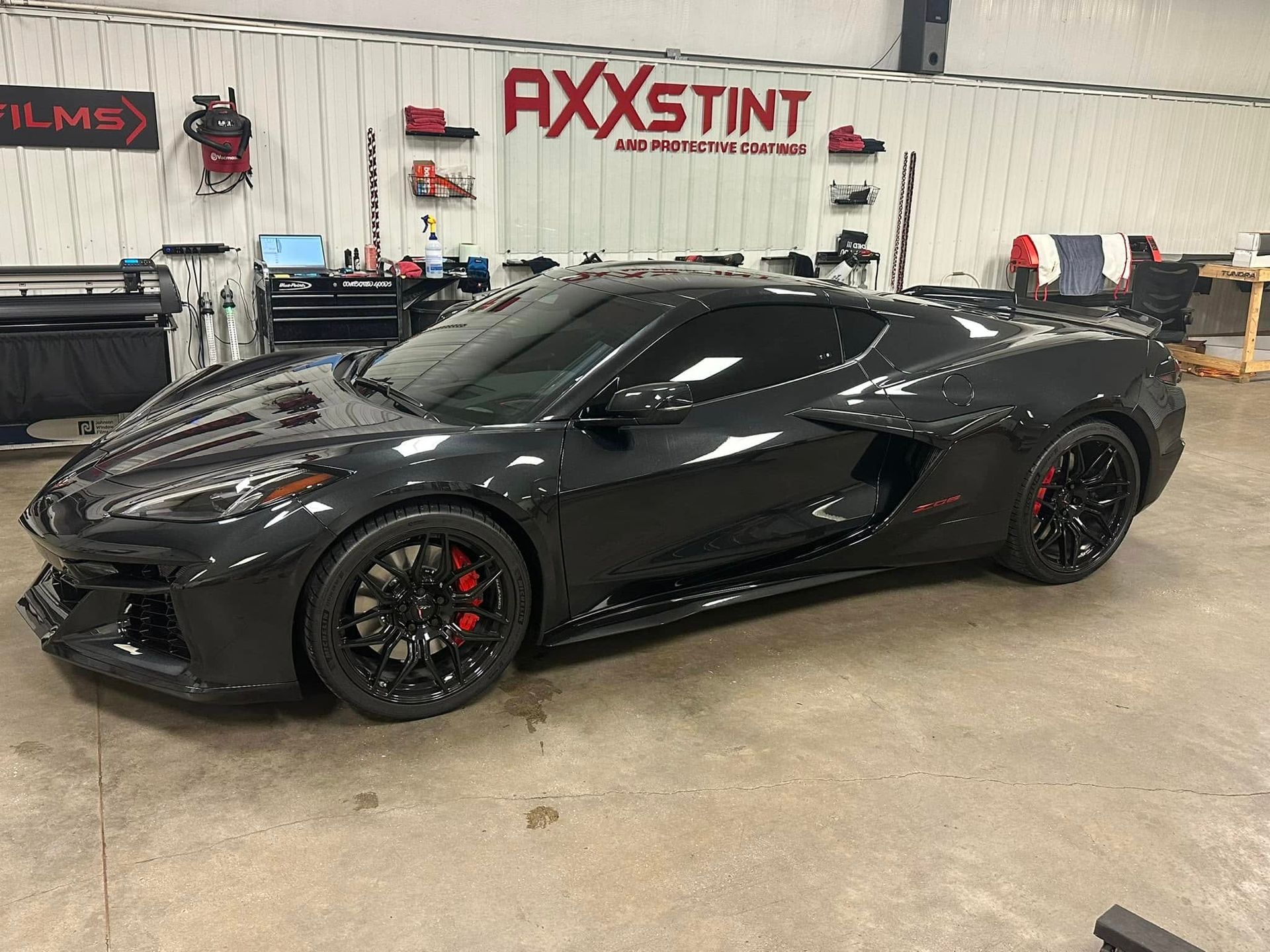 A black sports car is parked in a garage.