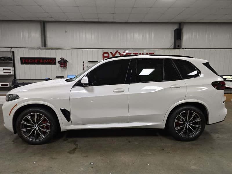 A white bmw x5 is parked in a garage.