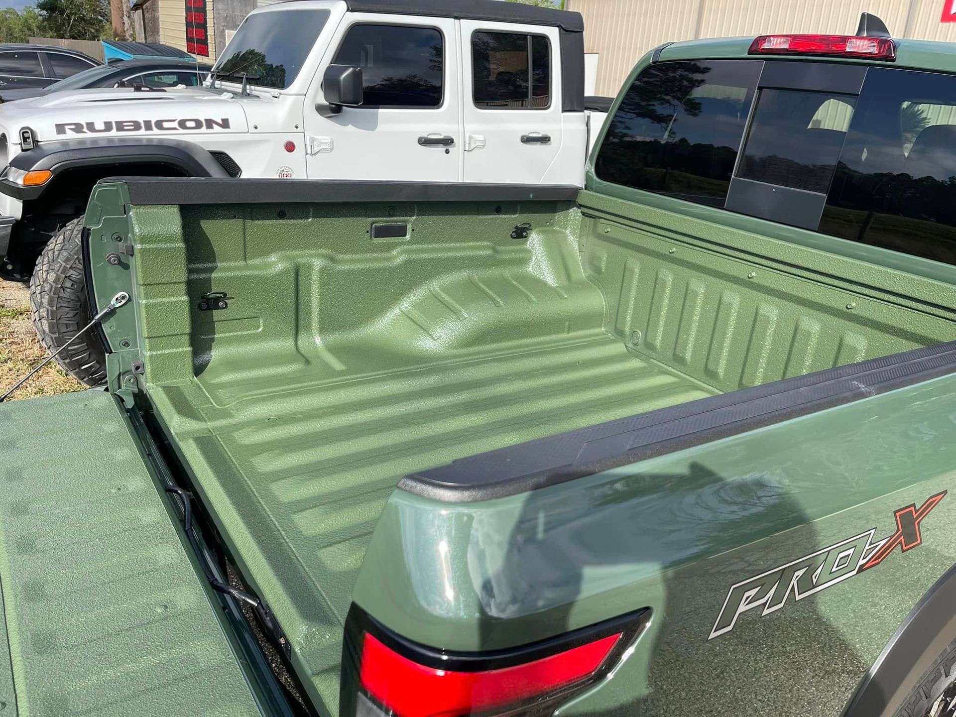 A green truck is parked next to a white truck.