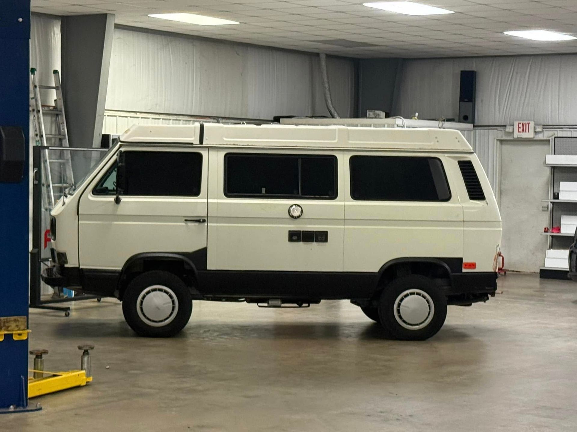 A white van is parked in a garage on a lift.
