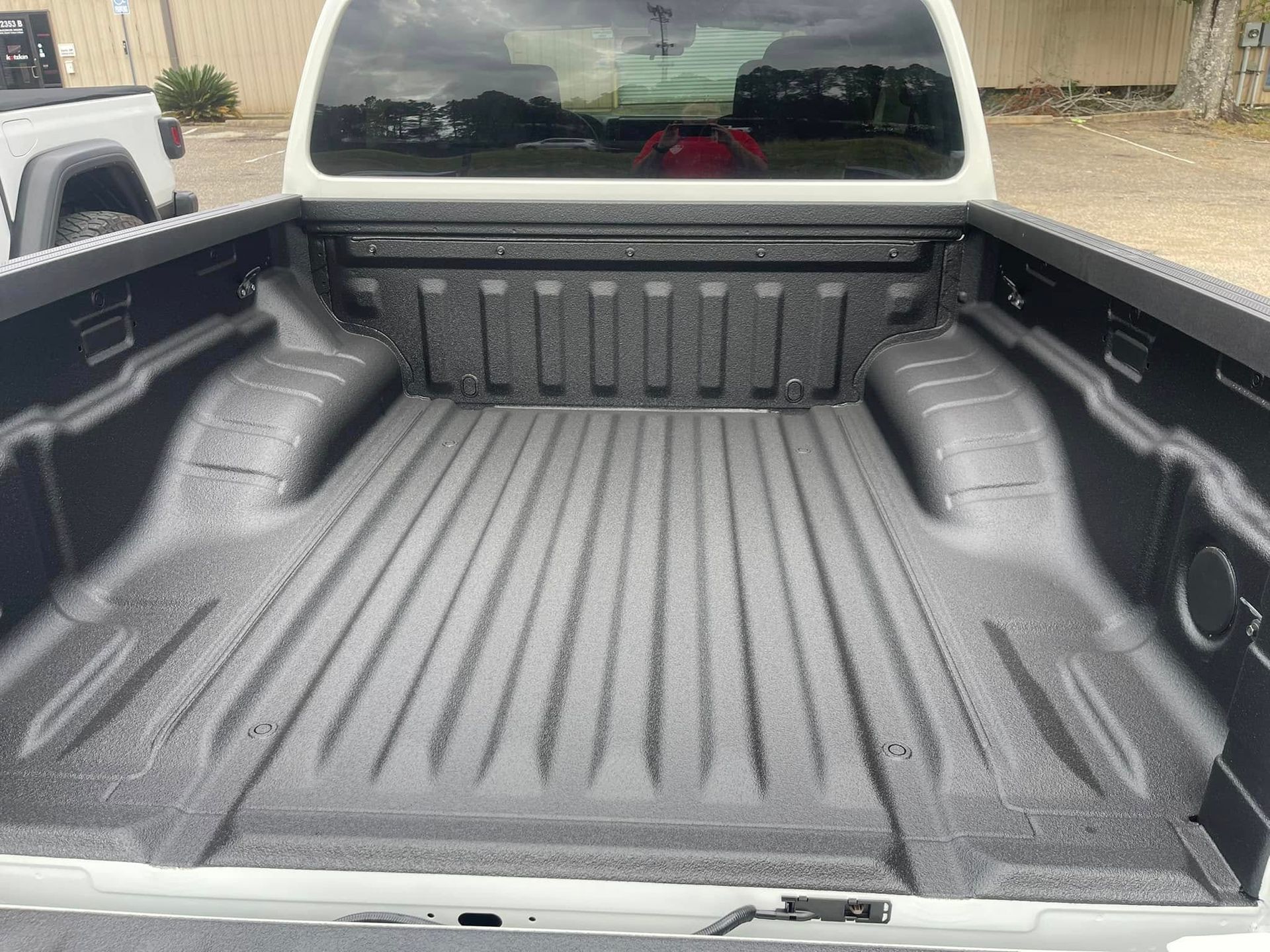 The bed of a white truck is painted black.
