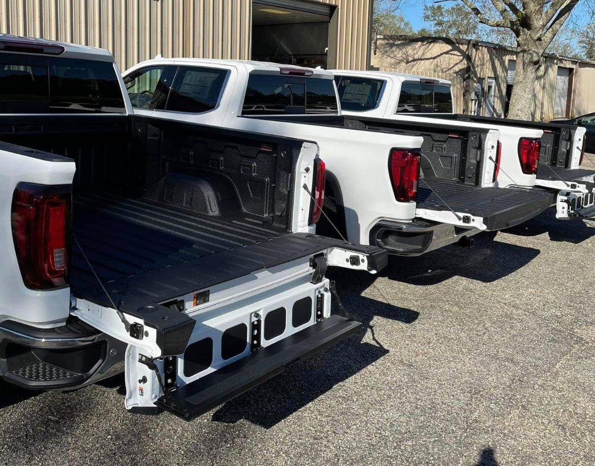 A row of white pickup trucks parked next to each other in a parking lot.