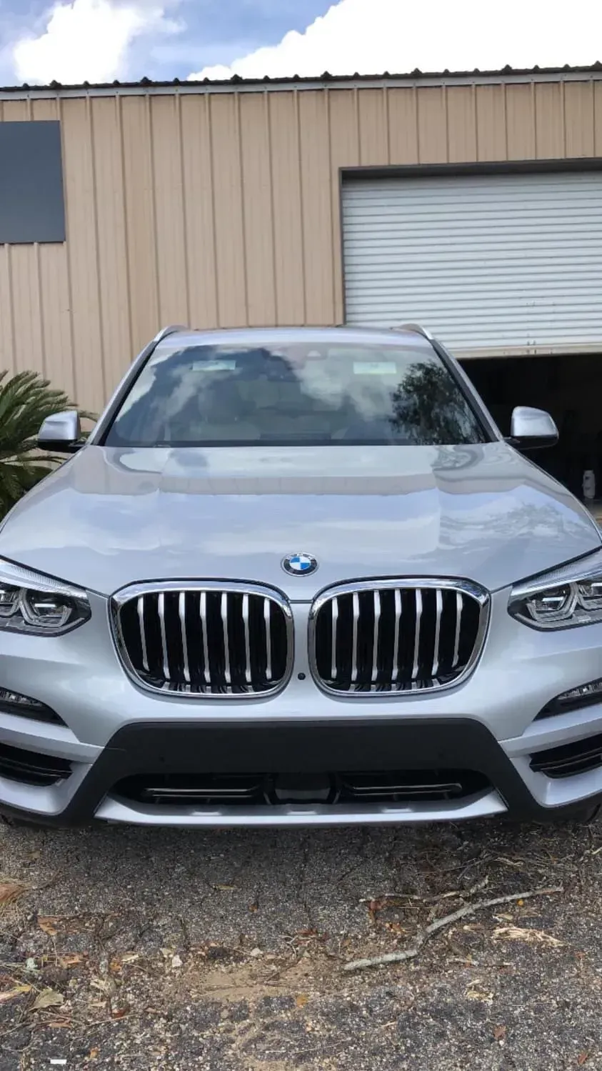A silver bmw x3 is parked in front of a garage door.
