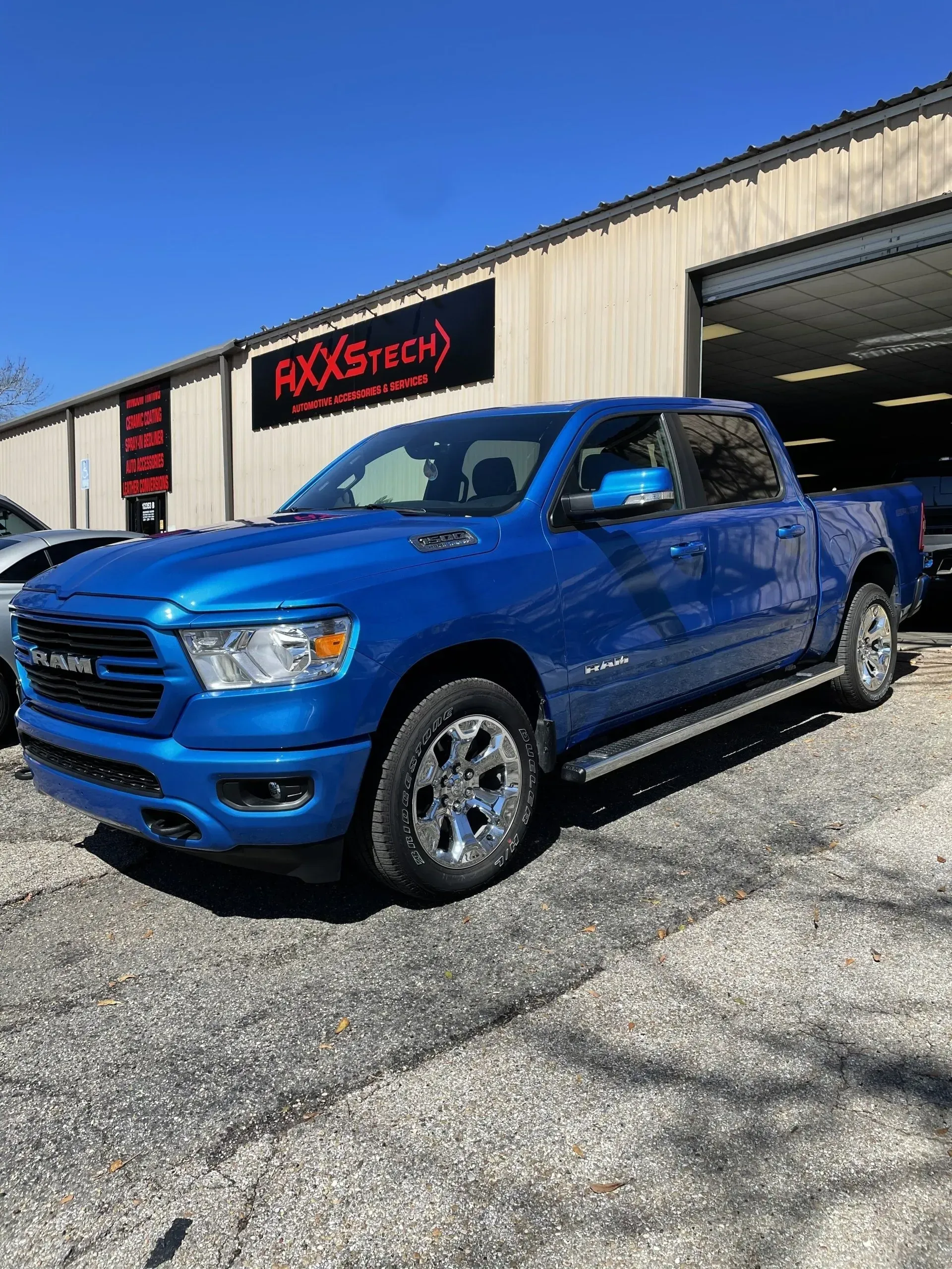 A blue ram truck is parked in front of a building.