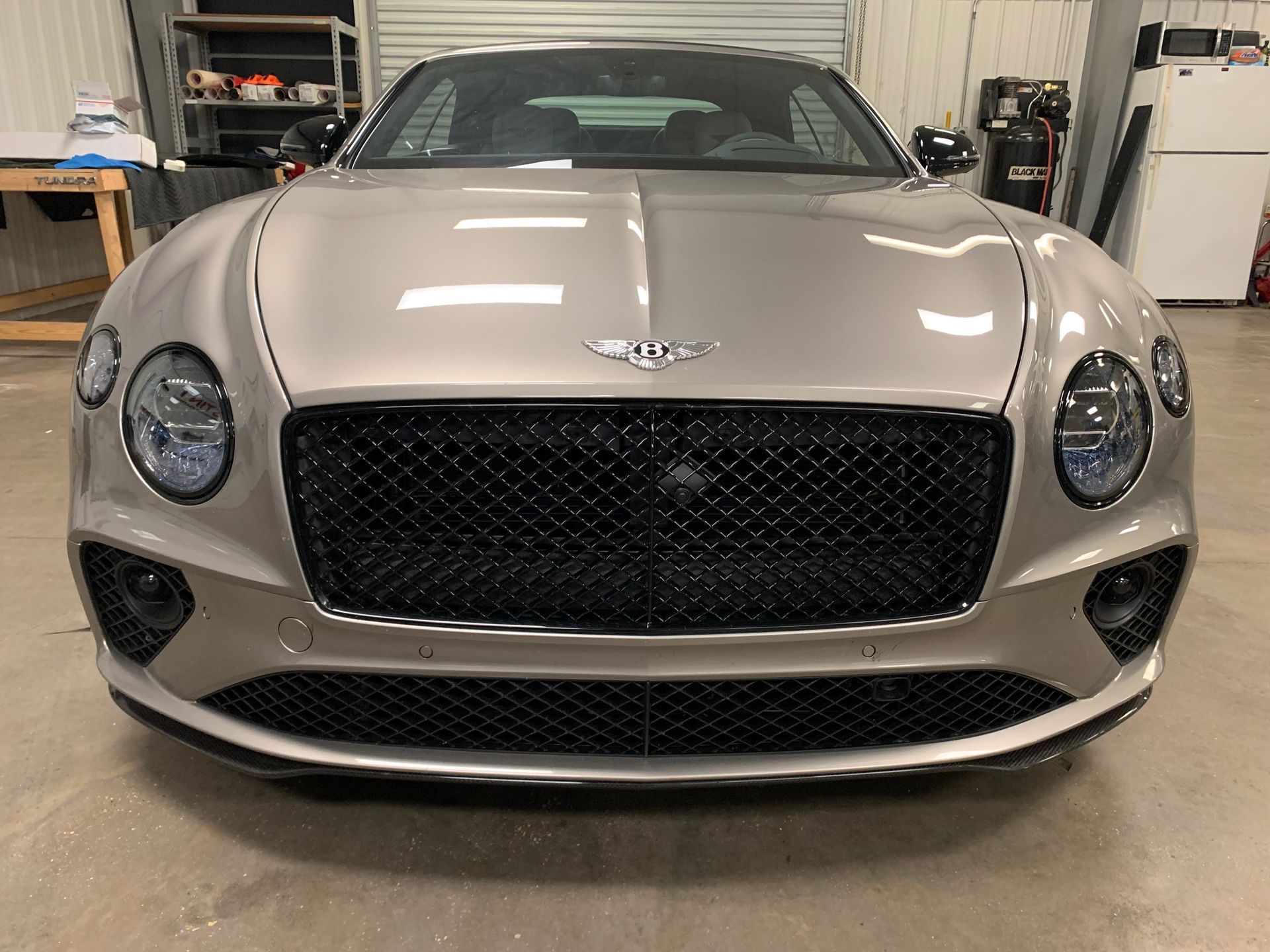 A gray car is parked in front of a building.