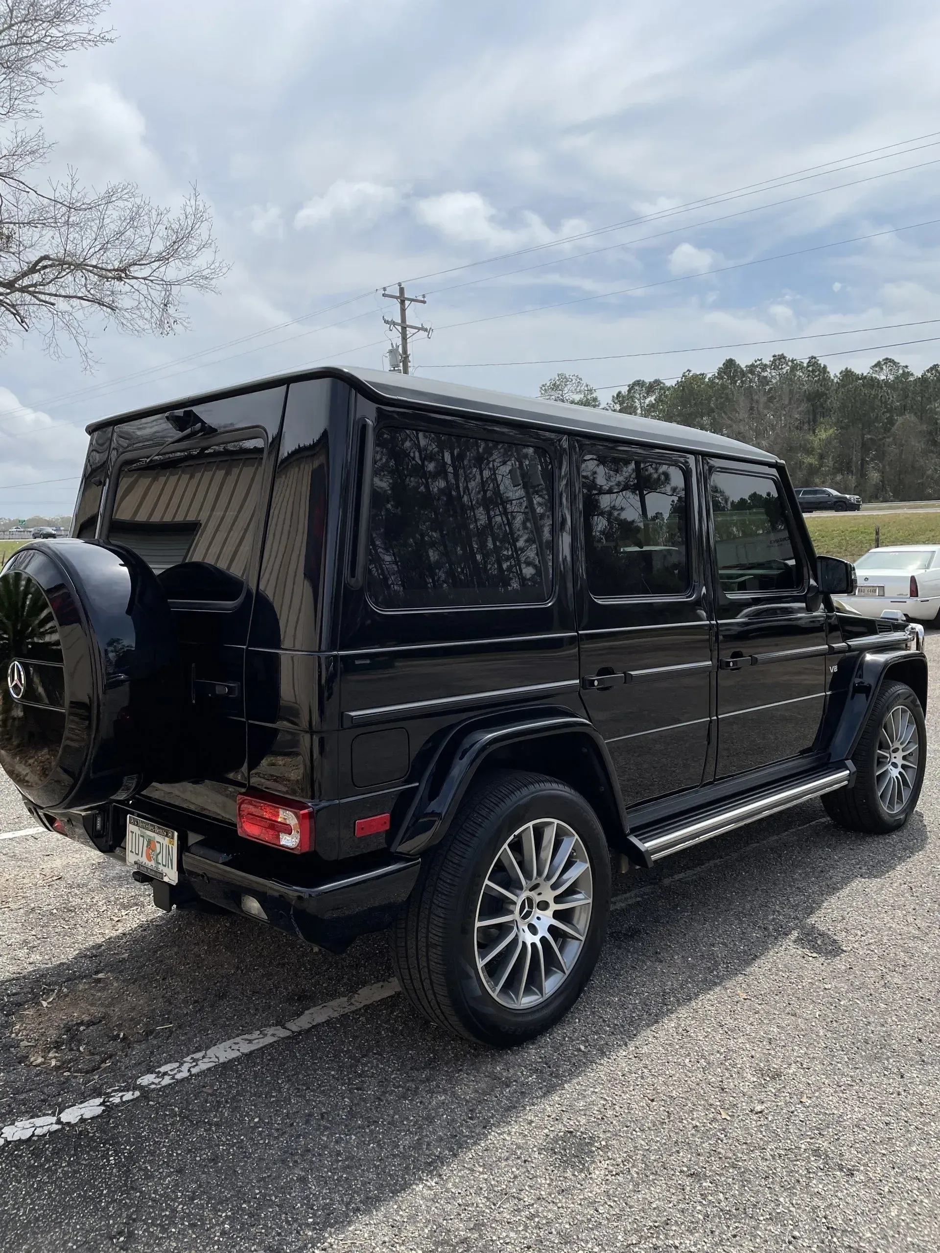 A black mercedes benz g class is parked in a parking lot.