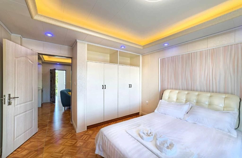Bedroom with bed, desk, TV, and window overlooking the sea, warm lighting.