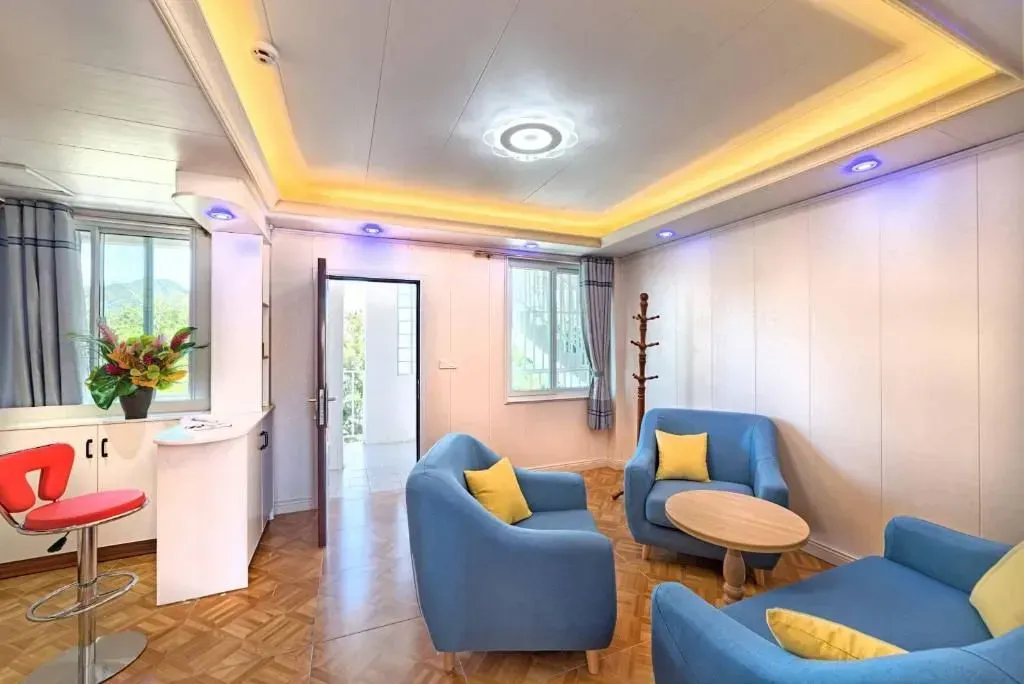 Living room with blue sofas, yellow pillows, a small table, and a bar stool.