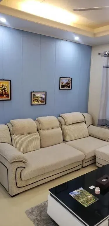 Living room with blue wall, light-colored sectional sofa, framed art, and black coffee table.
