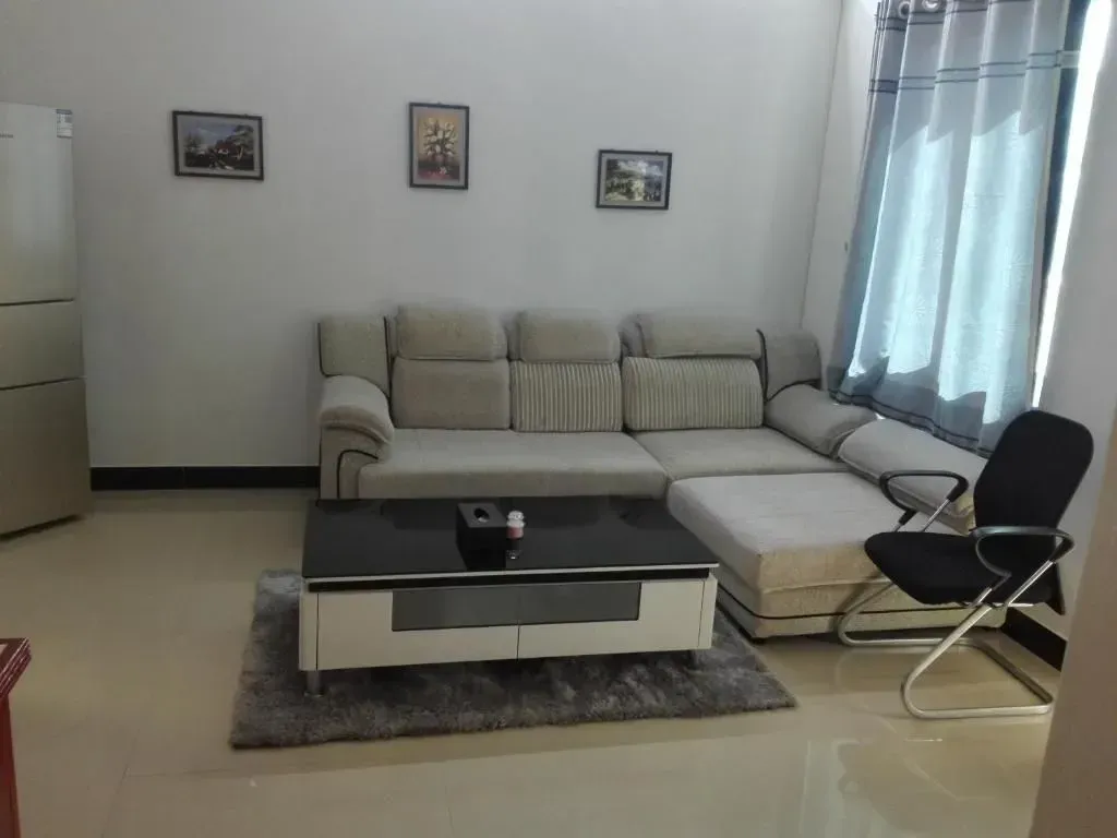 Living room with beige sectional sofa, black coffee table, chair, and art on white walls.