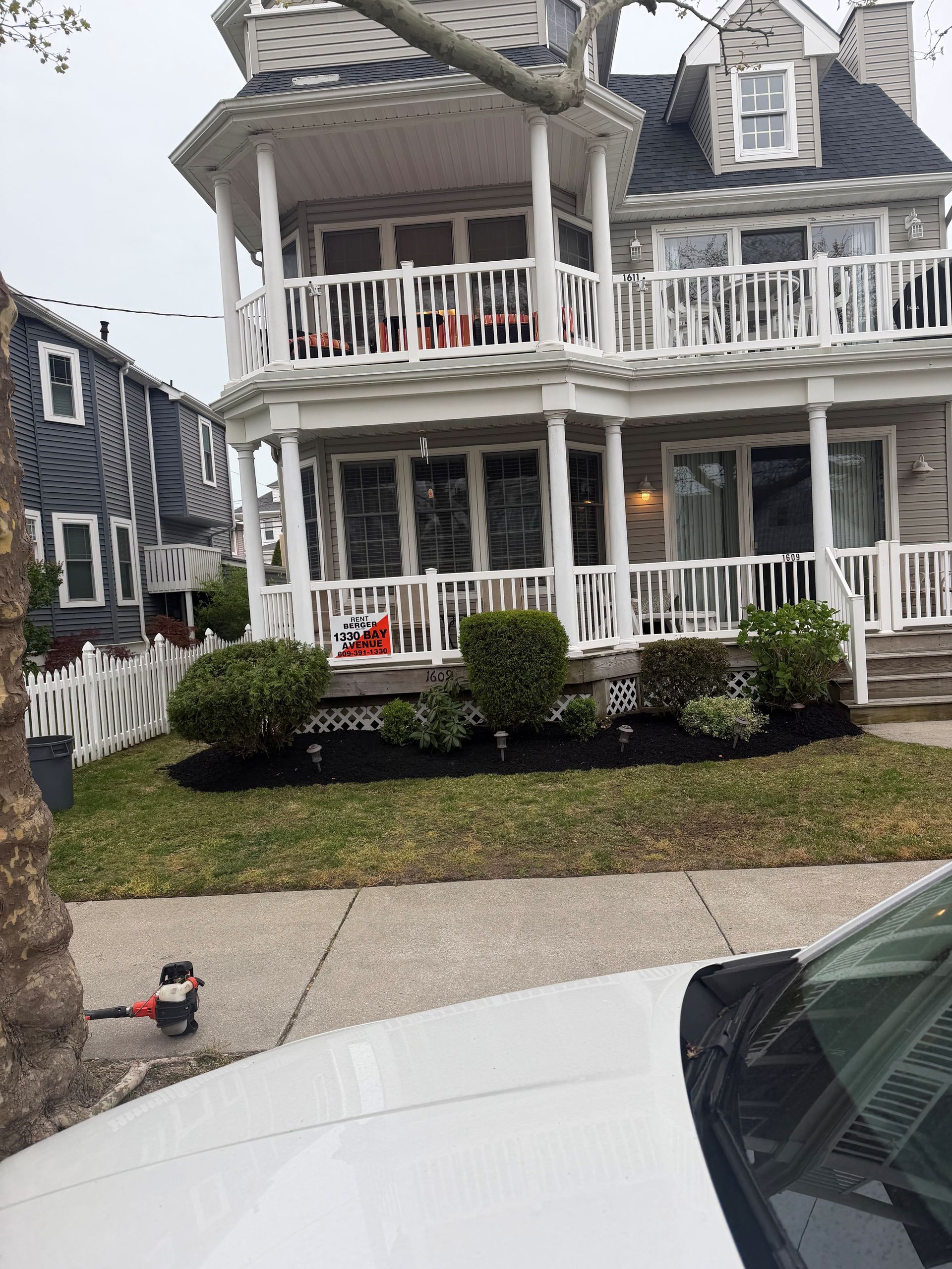 Victorian beach house in ocean city, nj with white porch railings, shrubs, and a pigeon on the sidewalk in front