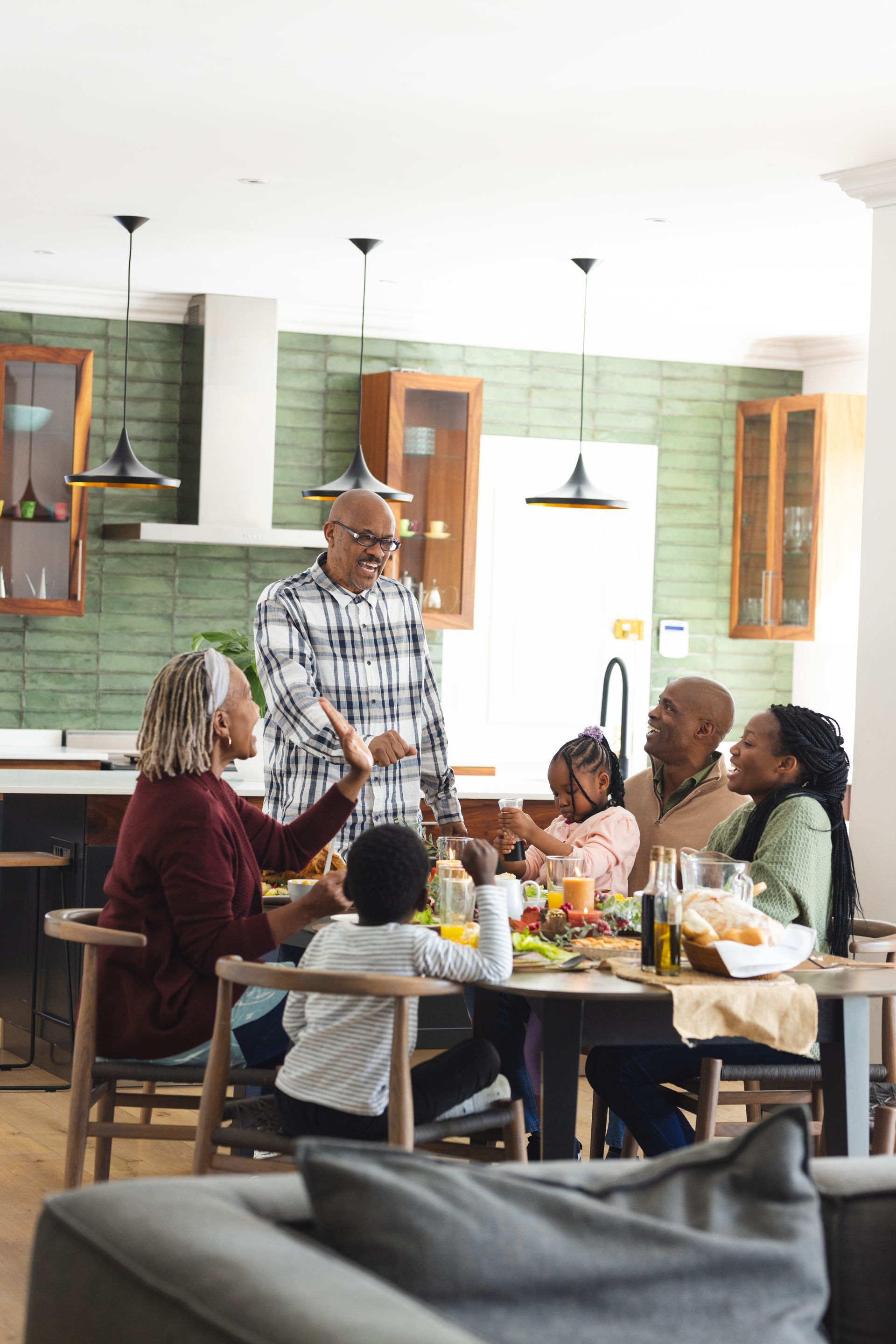 Family gathered around a dining table in a bright kitchen, sharing a meal and conversation.