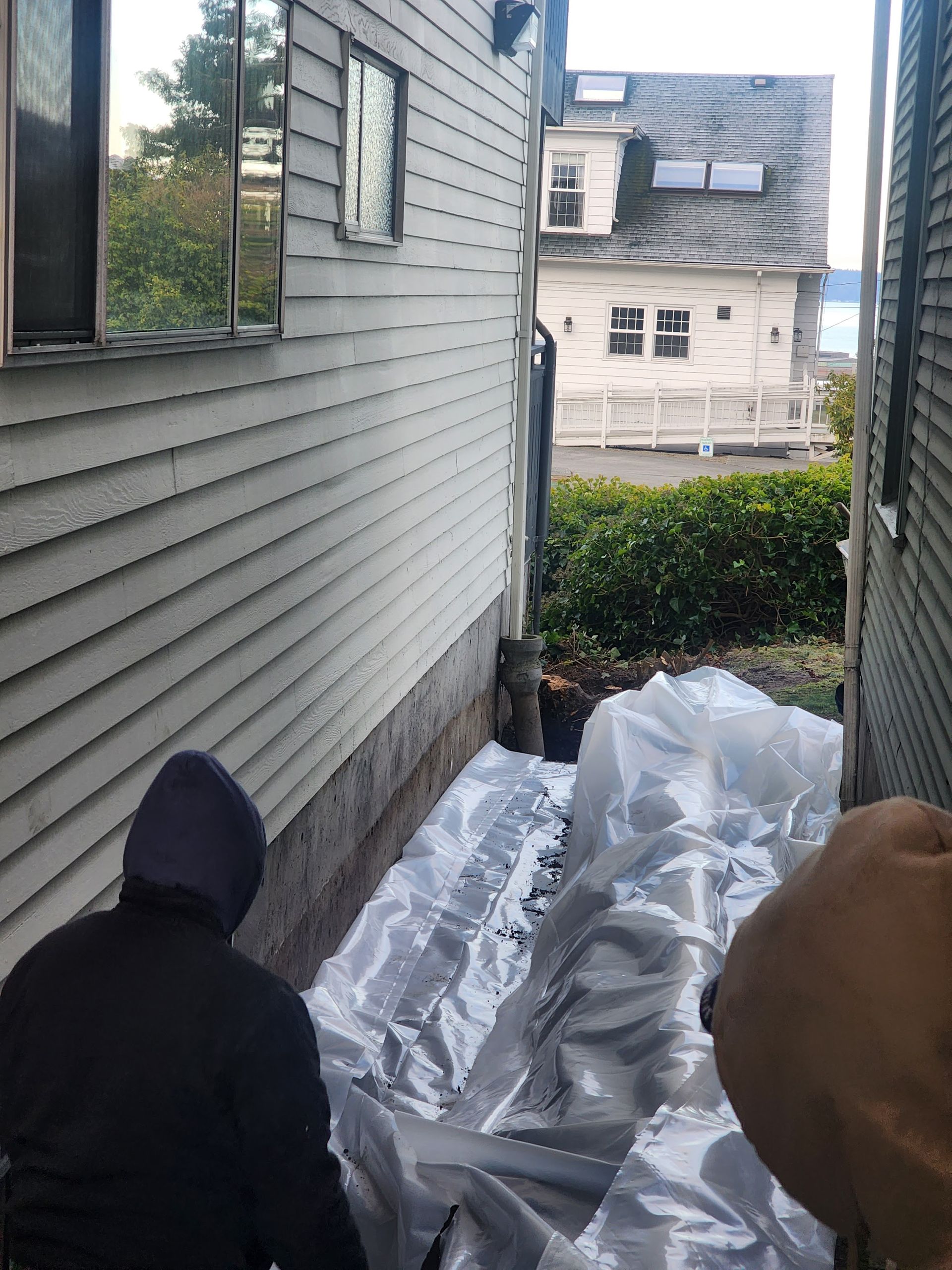 Two people near a narrow space between two buildings, covered with plastic sheeting.