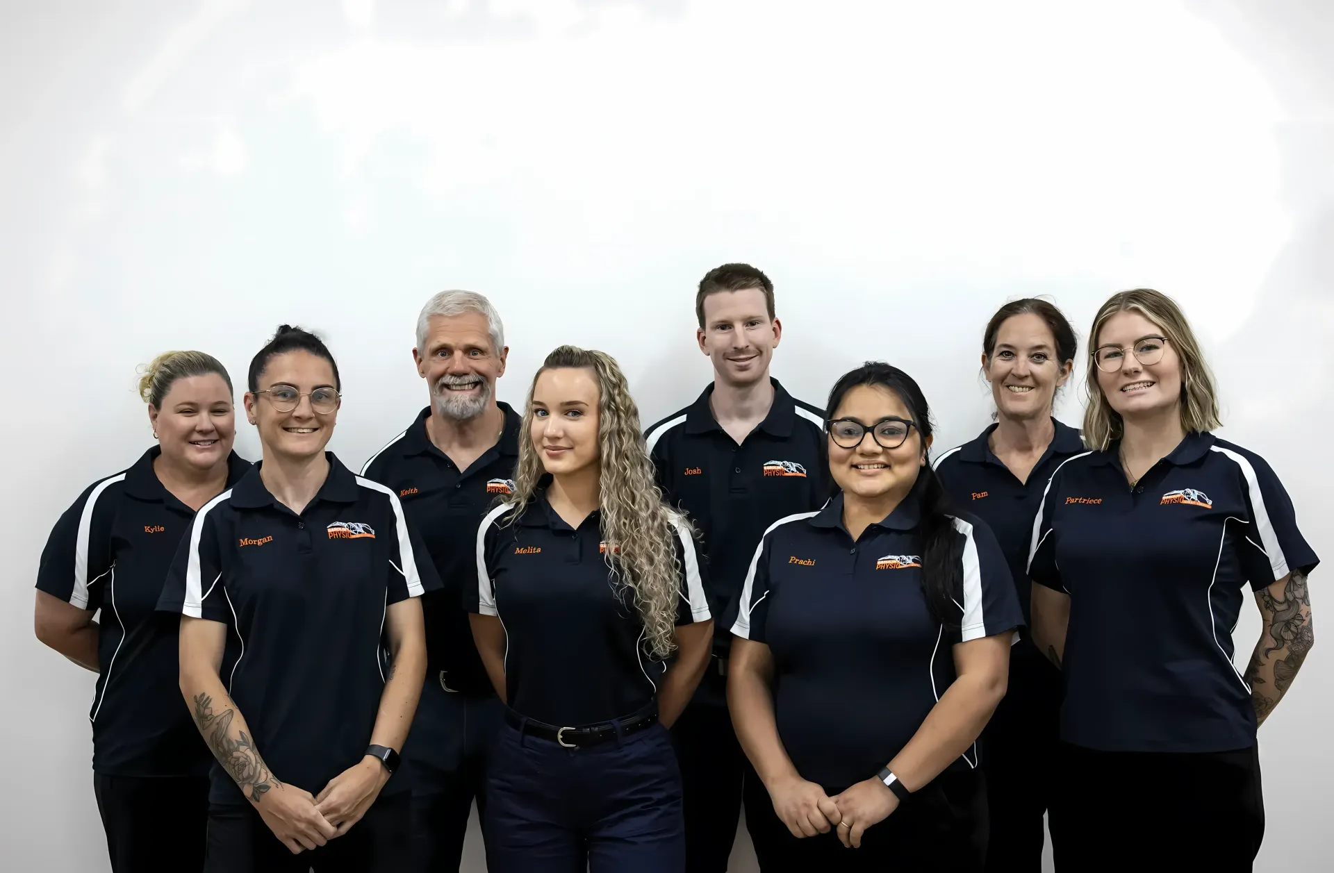 Team of Eight People in Navy Blue and White Shirts — Barolin Physiotherapy Services in Bundaberg South, QLD