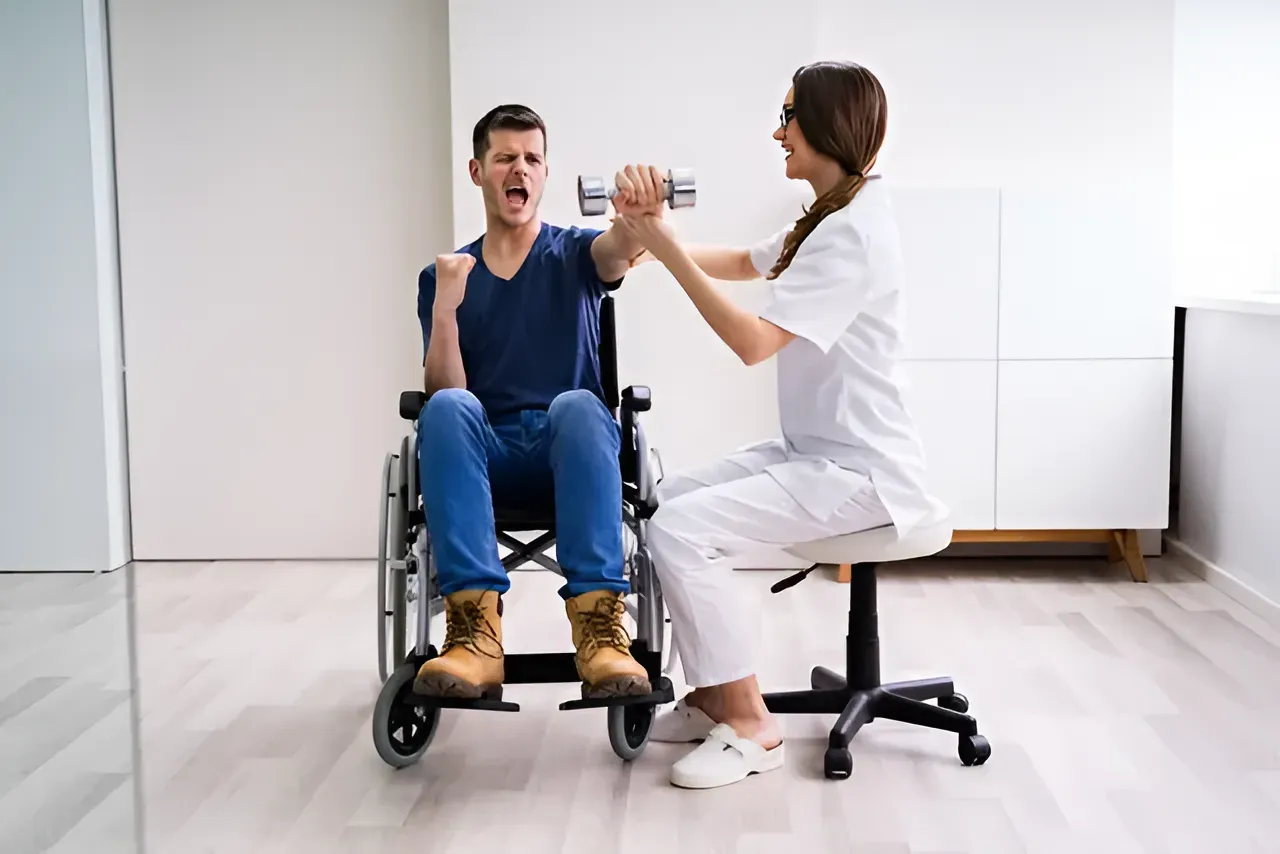 Man in Wheelchair Lifts Dumbbell With Assistance — Barolin Physiotherapy Services in Bundaberg South, QLD