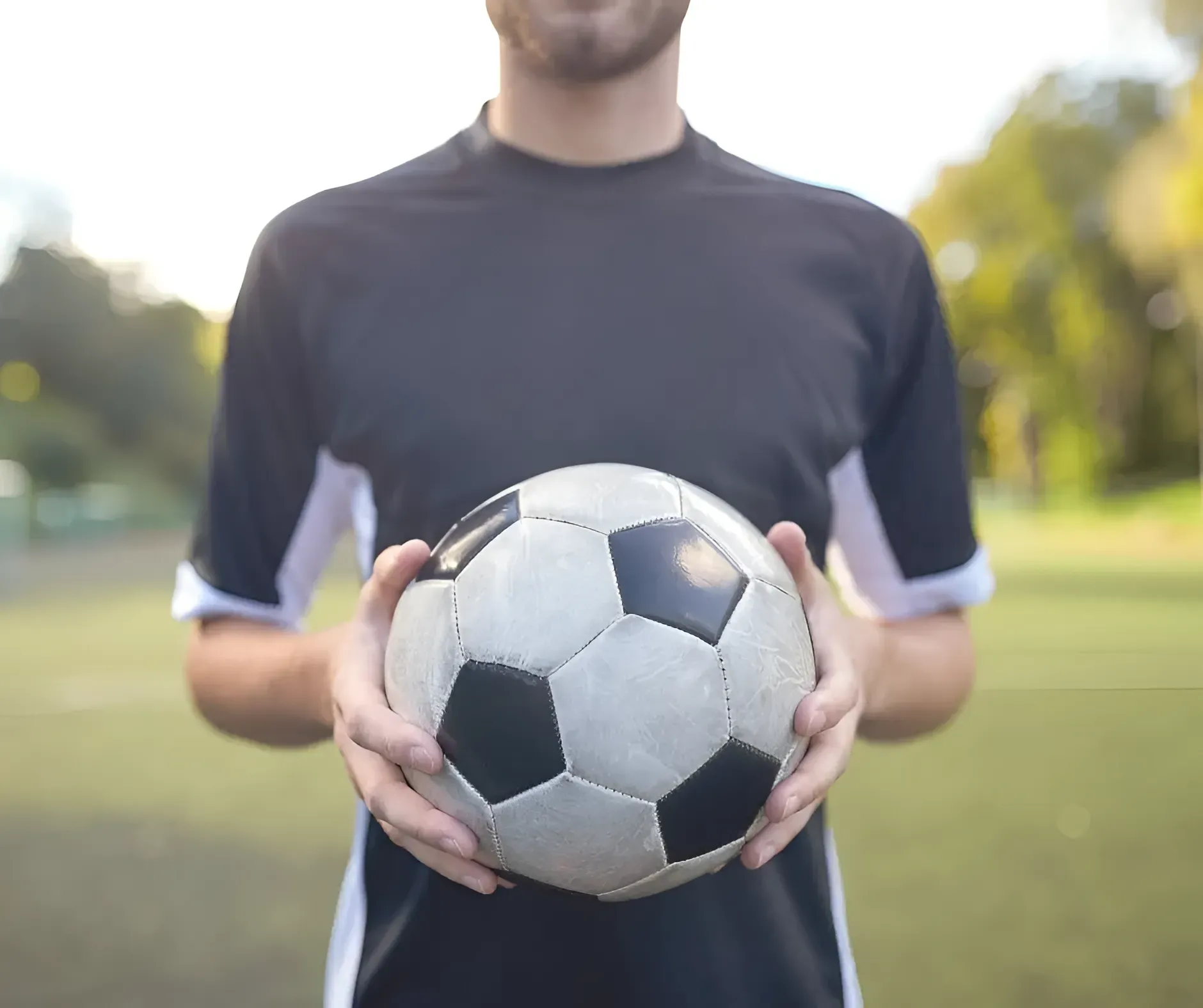 Man Holding Soccer Ball on a Green Field — Barolin Physiotherapy Services in Bundaberg South, QLD