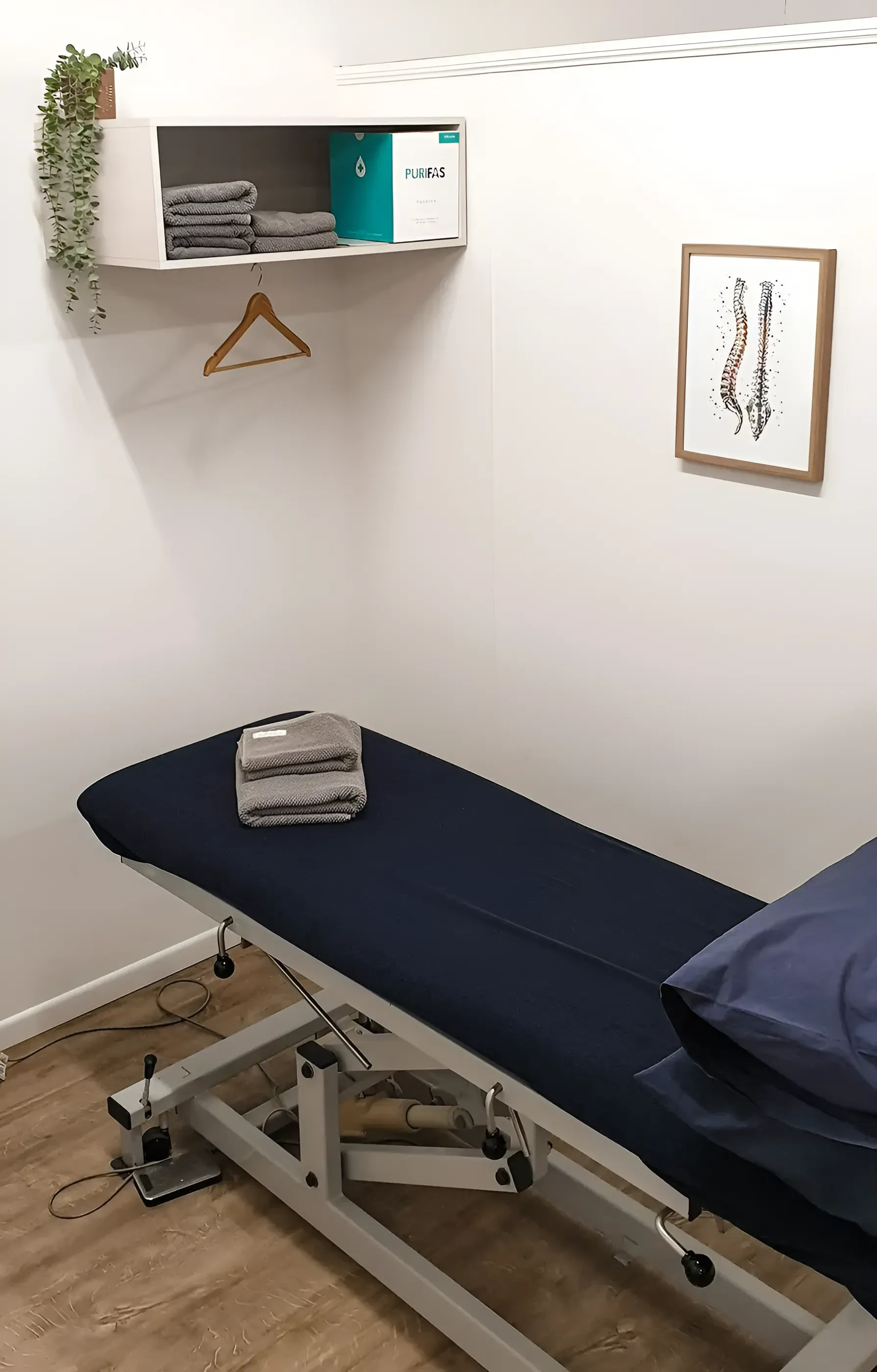 A Massage Room With a Blue Table, Cabinet With Towels — Barolin Physiotherapy Services in Bundaberg South, QLD