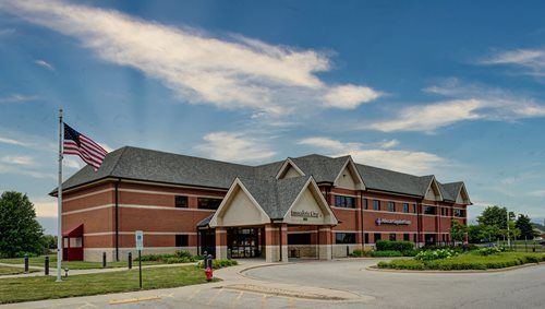 Brick building with American flag, blue sky, and a circular driveway.