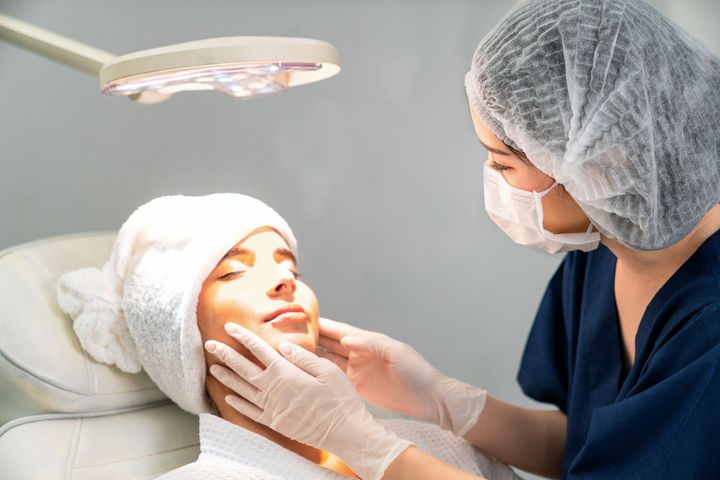 Person receiving facial treatment from professional in spa or clinic.