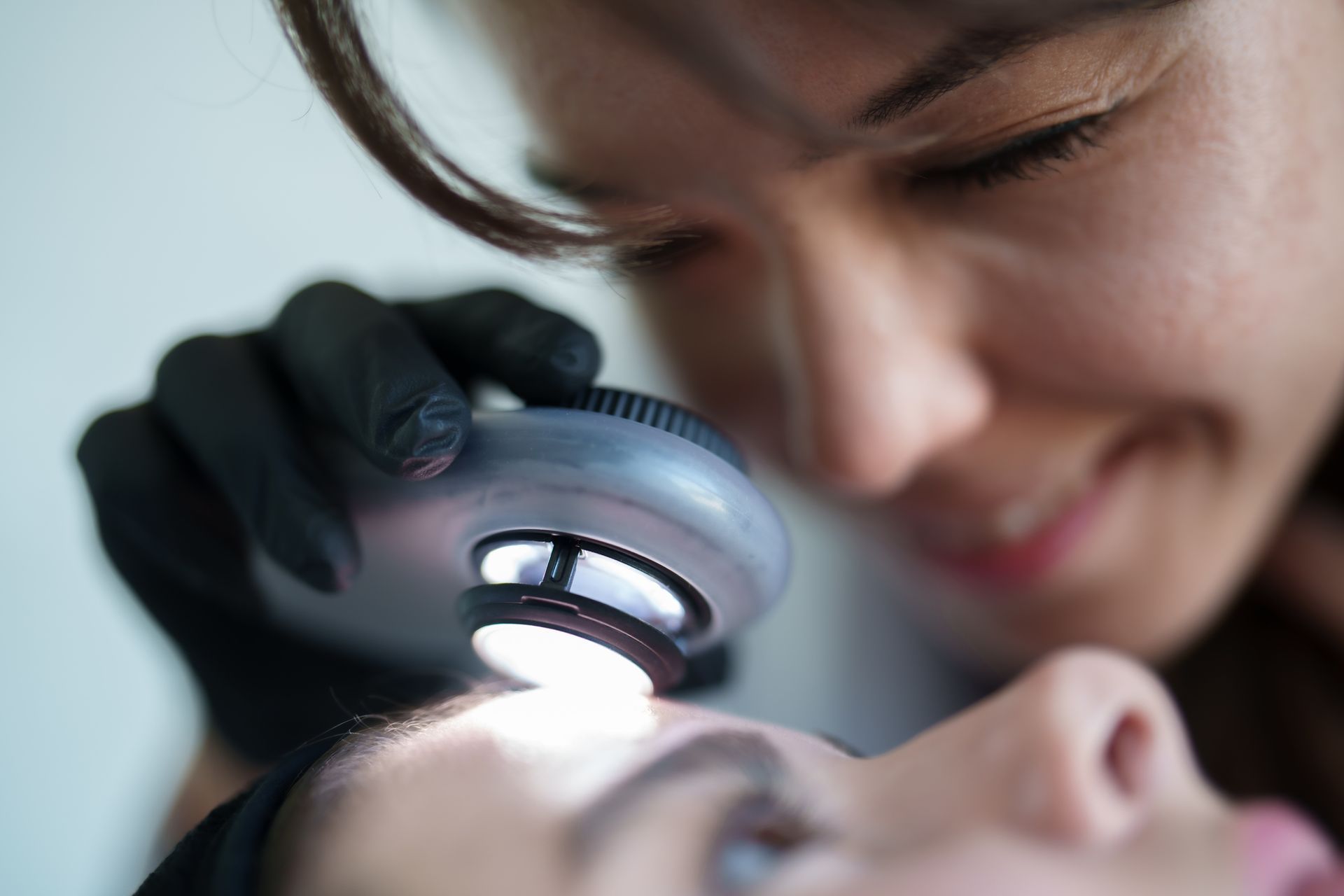 A dermatologist is examining a patient’s skin.