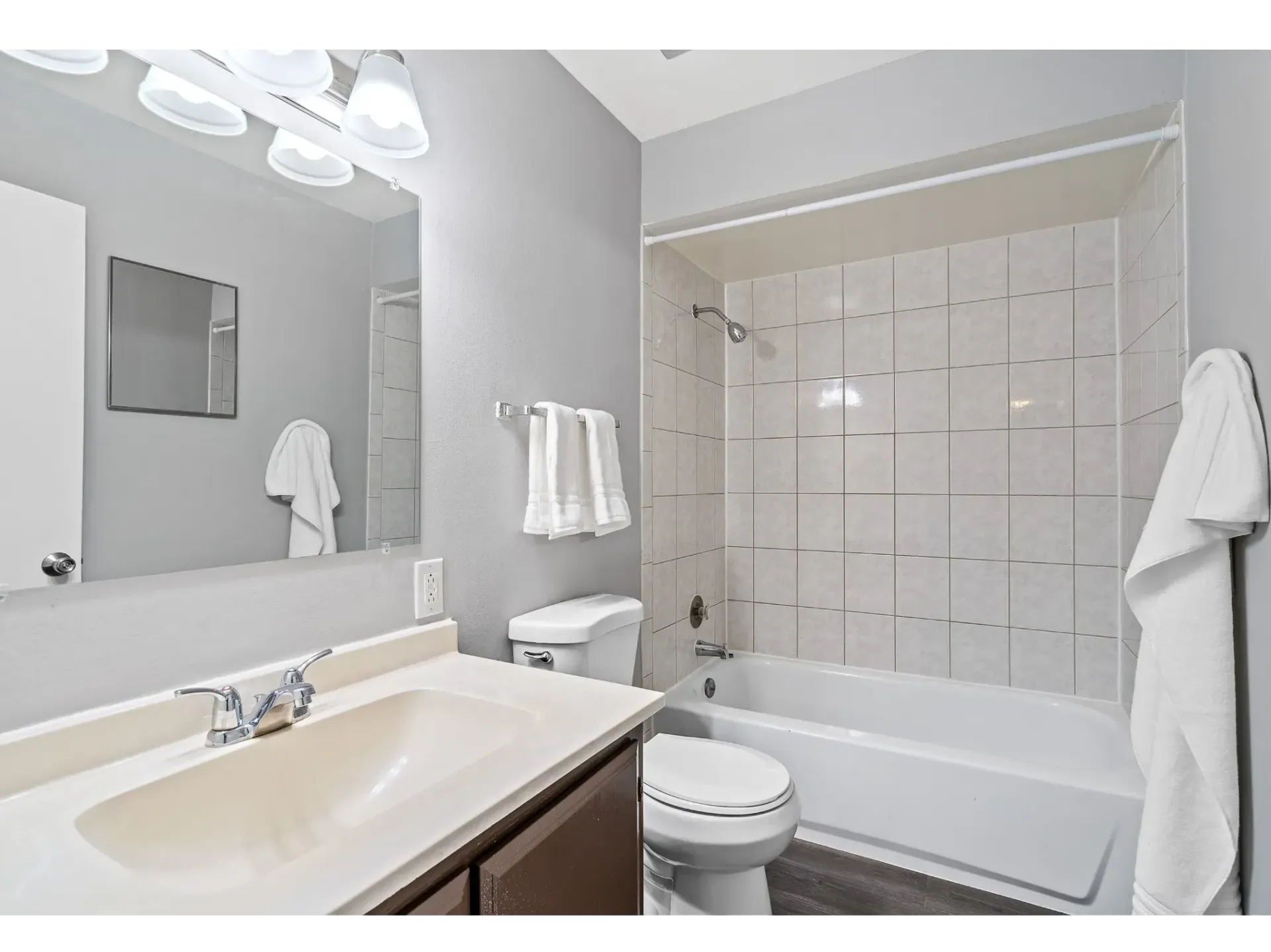 Modern bathroom featuring a sink, toilet, and bathtub with shower at Bartlett Lakes, offer West Chicago apartments for rent.