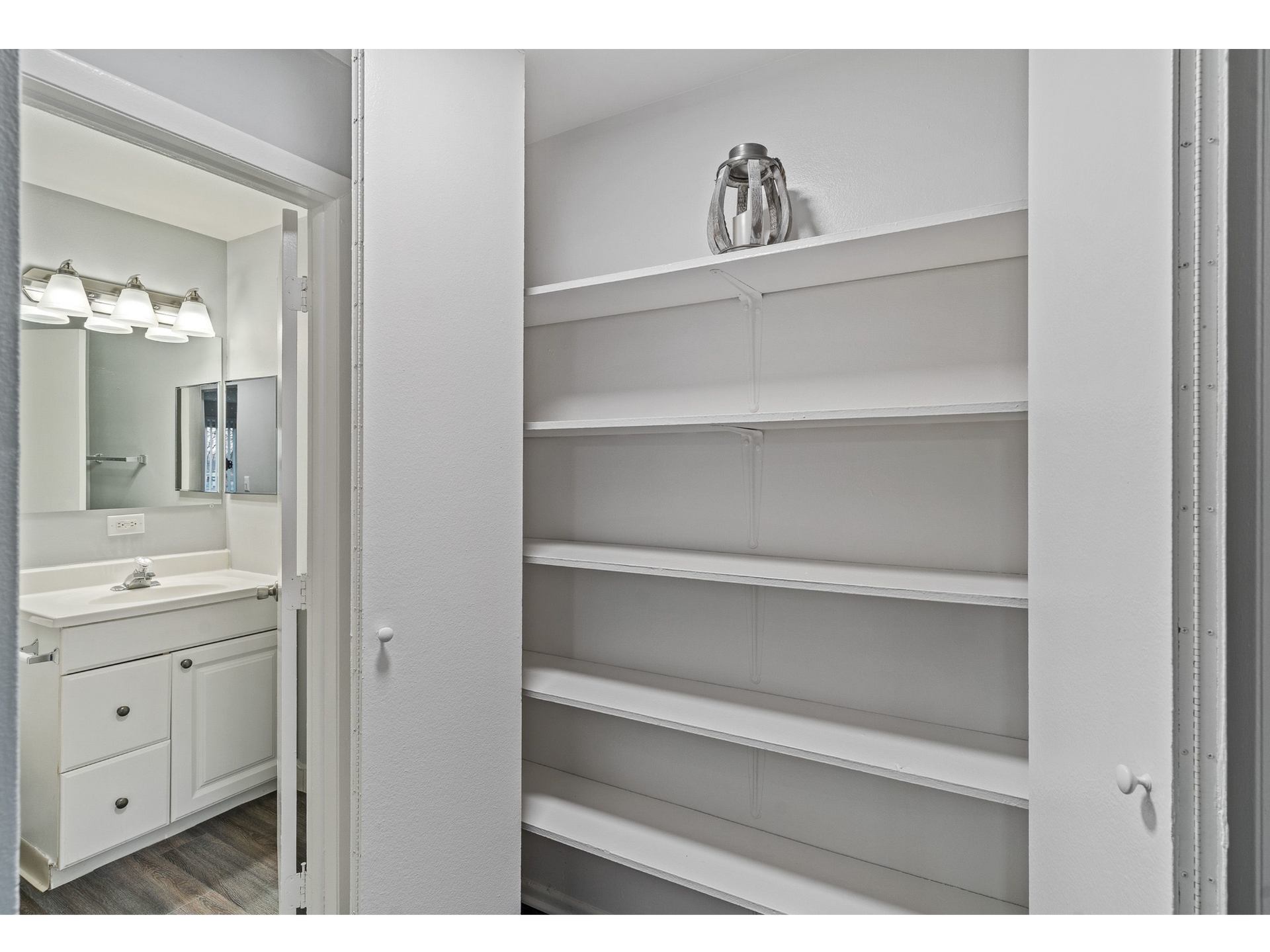 Open built-in white shelving closet beside a bathroom vanity.