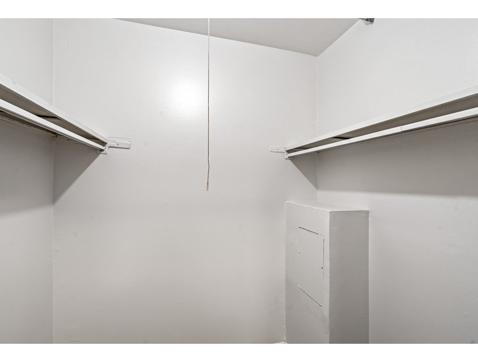 White walk-in closet with two parallel clothing rods and shelves.