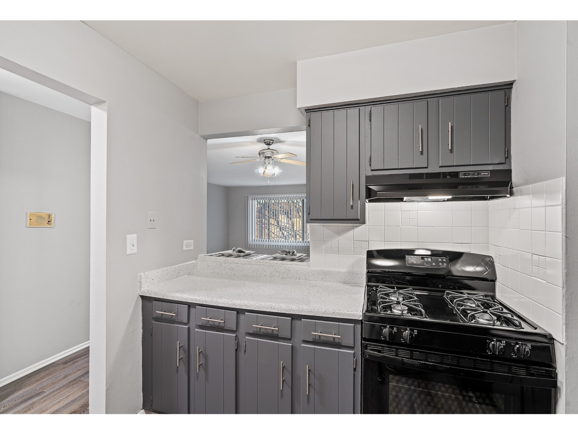 Kitchen with gray cabinets, white tile backsplash, and a black gas range.