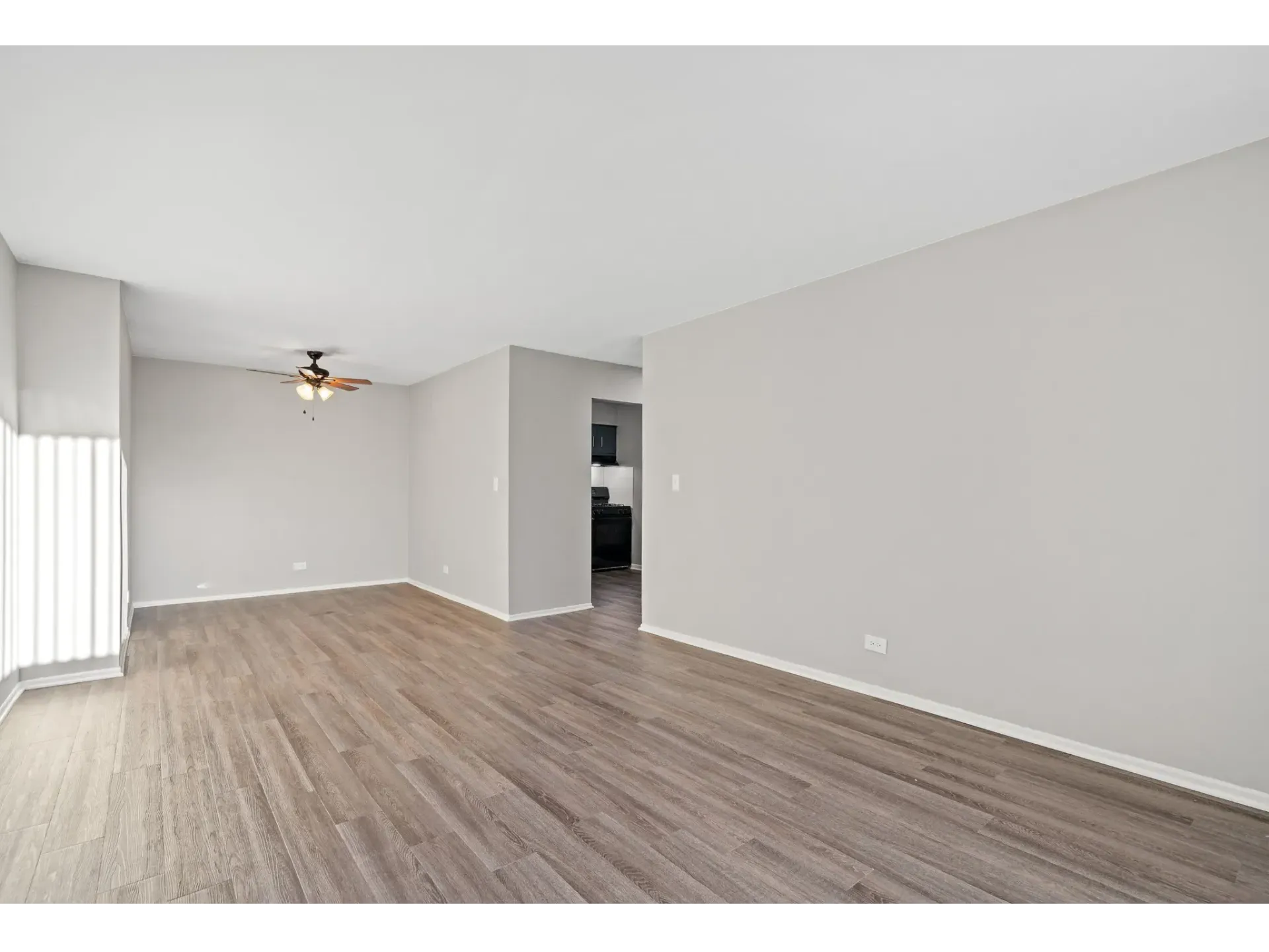 Spacious living area with light-colored walls and wooden floor at Bartlett Lakes, offer apartments for rent in West Chicago, IL.