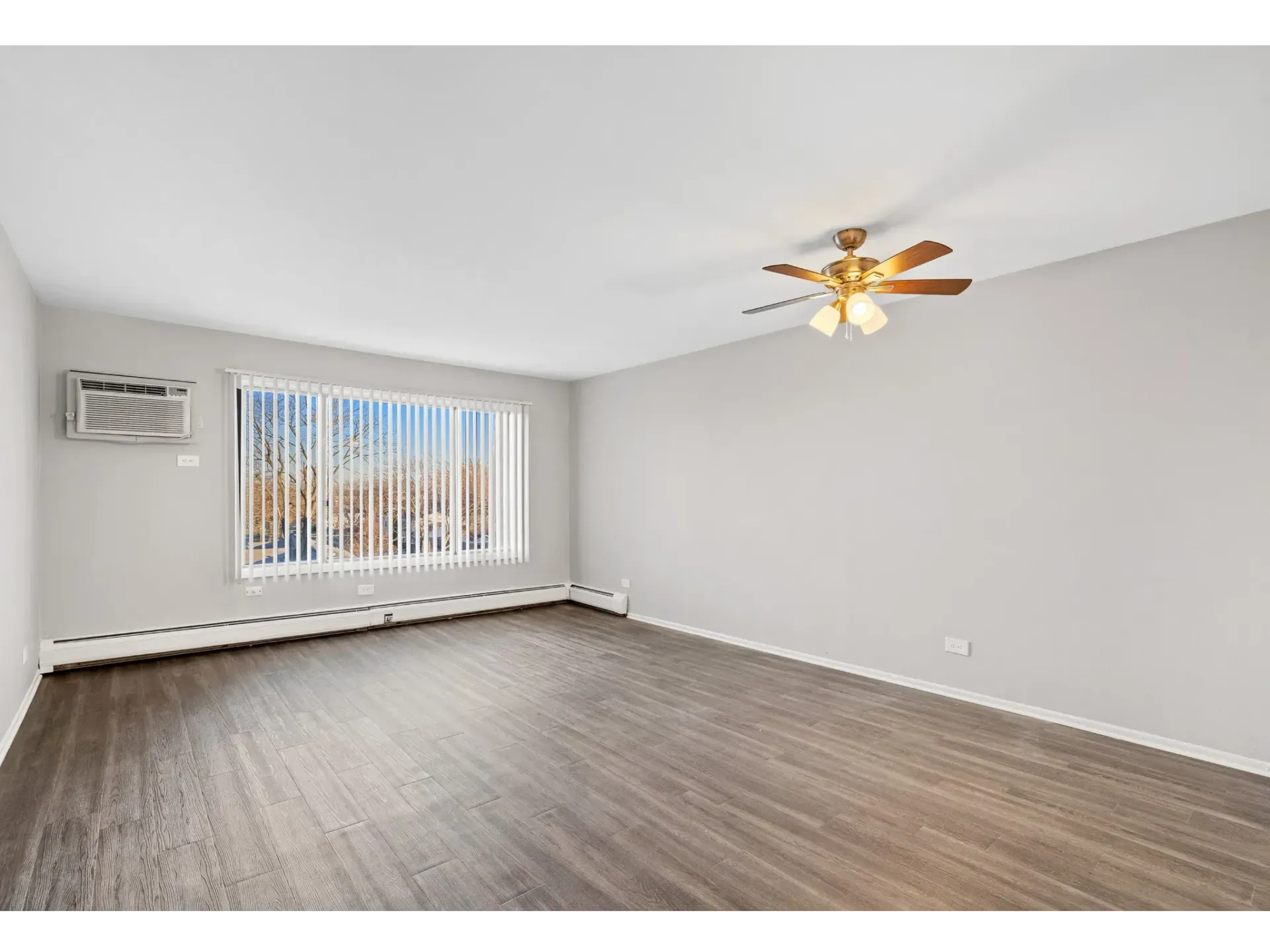 Spacious living room with ceiling fan and large window at Bartlett Lakes, offer Bartlett apartments for rent in West Chicago.