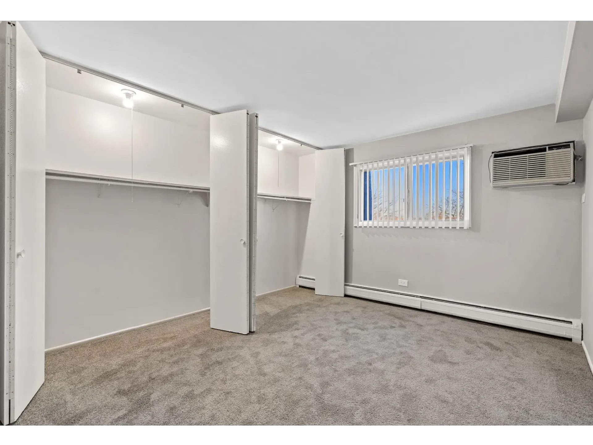 Interior view of a vacant apartment bedroom with built-in closets and a window at Bartlett Lakes, offer Bartlett apartments for rent in West Chicago.