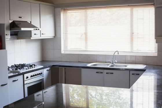 A kitchen with white cabinets and black counter tops