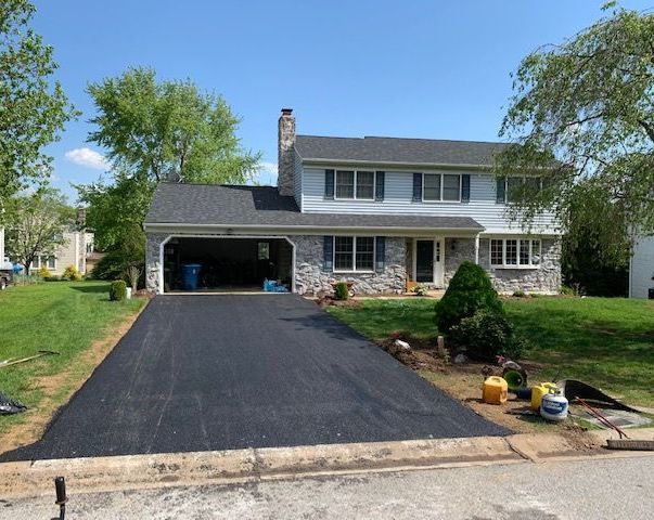 image of asphalt drive in lancaster, PA. You can see a newly finished asphalt driveway witha white house in the back.