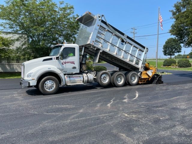 image of a asphalt company truck dumping asphalt  on parking lot.