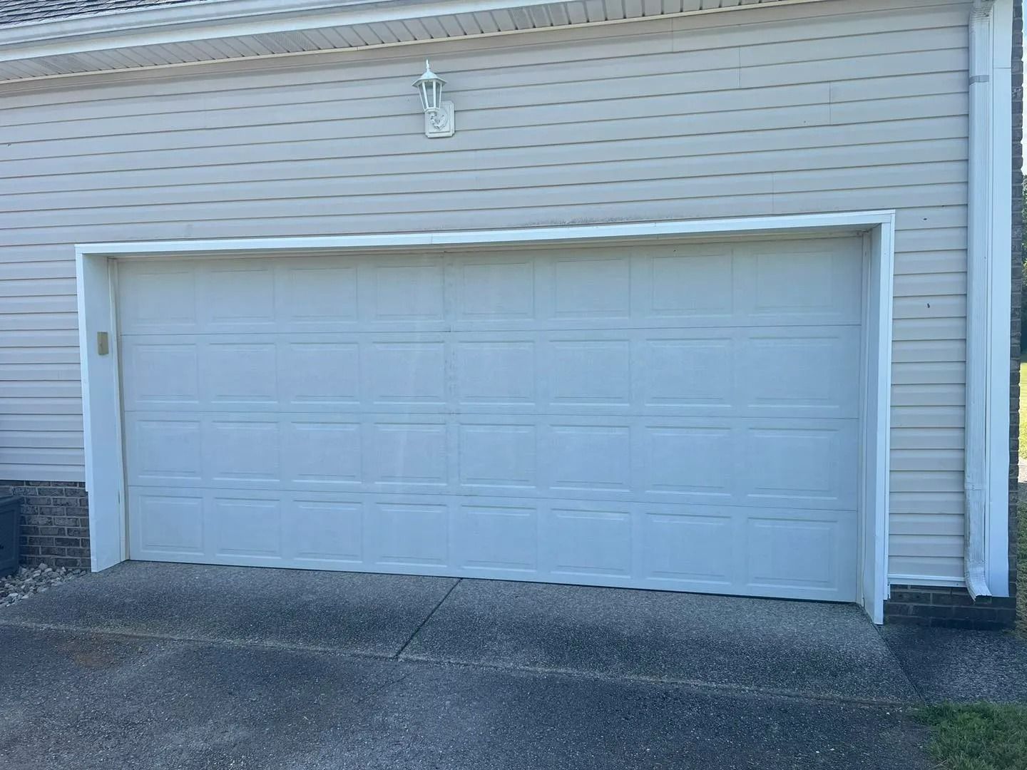 White garage door on a beige house with concrete driveway.