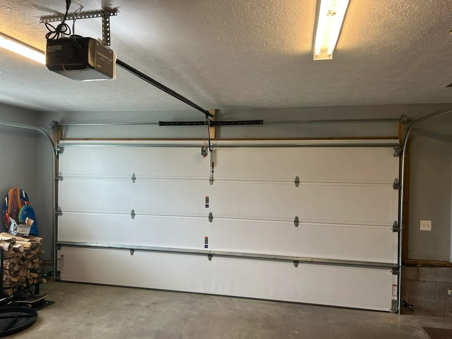 White closed garage door inside a garage, with an opener mounted on the ceiling.