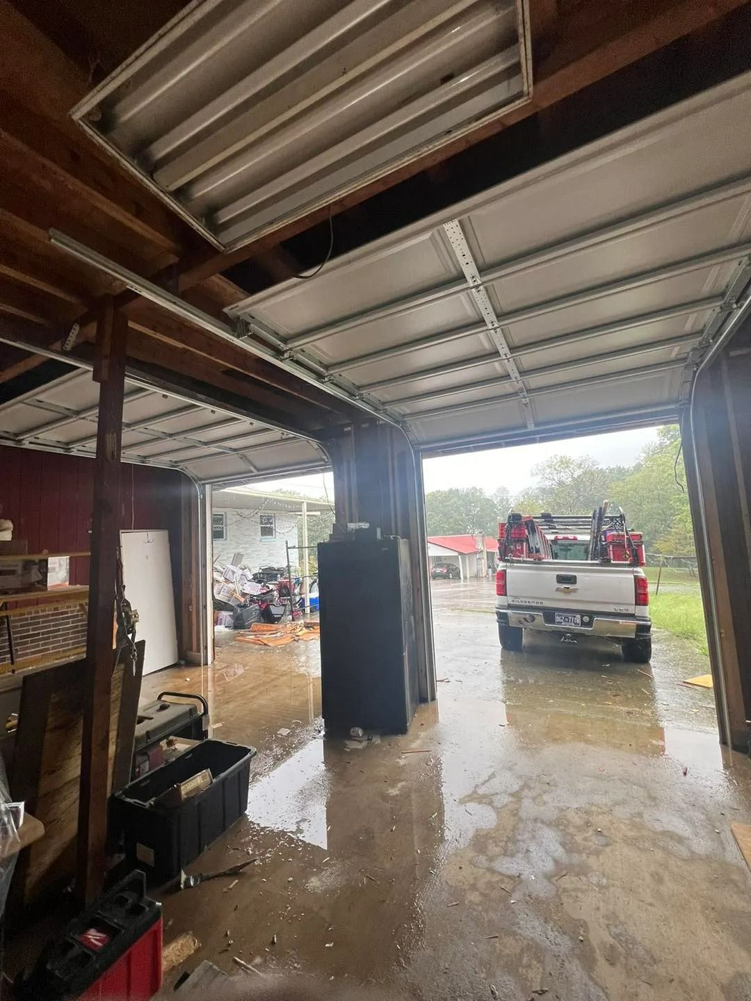 Interior of a garage with open door, truck outside, wet floor.