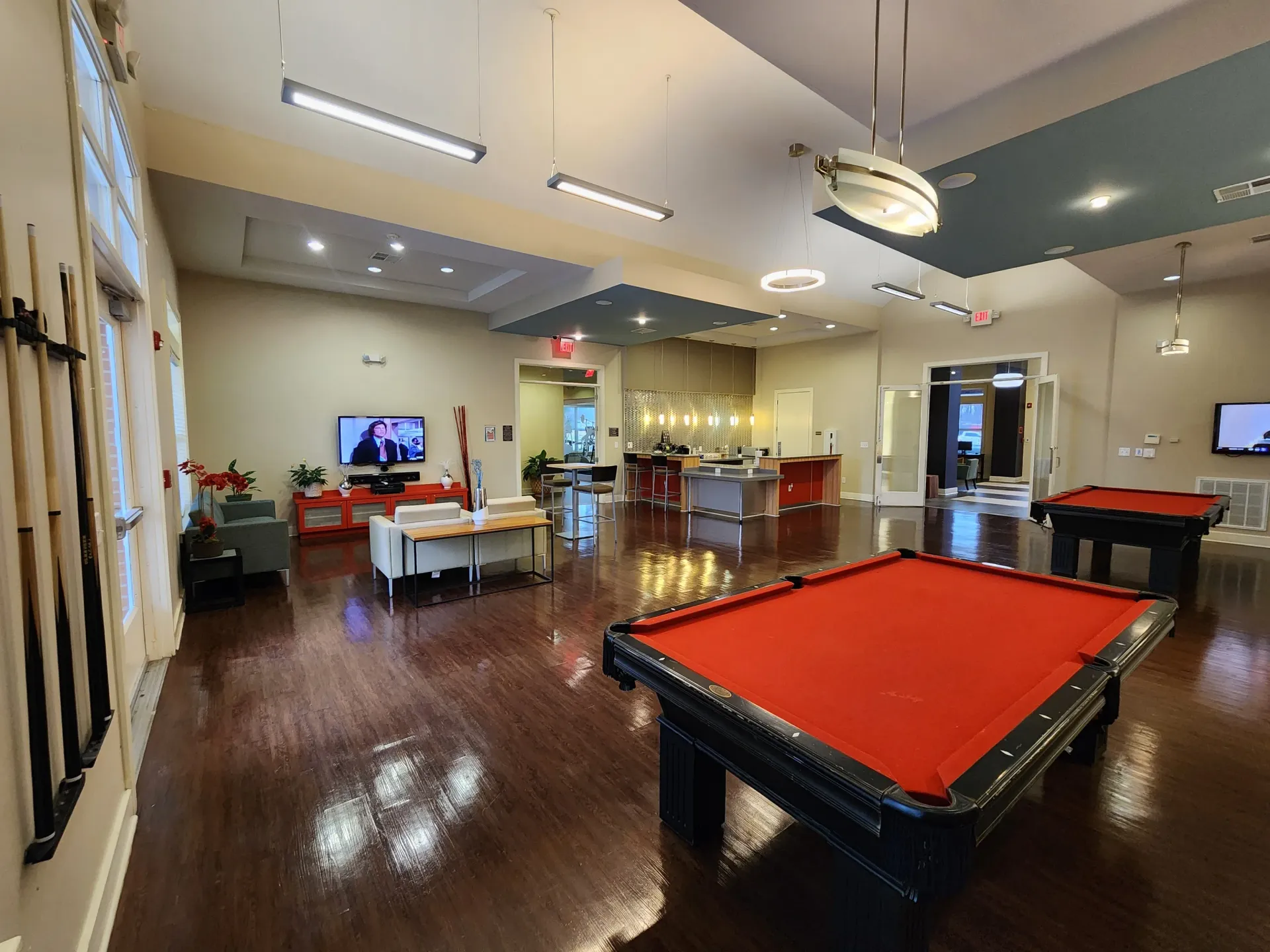 Game room with red pool table, polished wood floor, TV, and lounge seating under ceiling lights