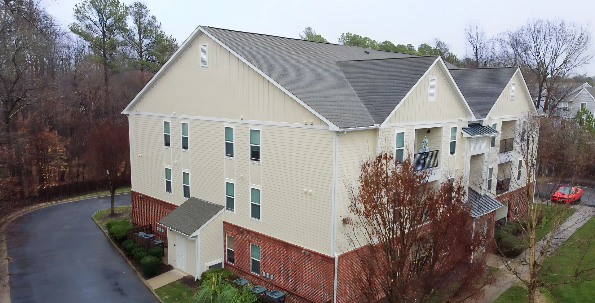 A sandy beach volleyball court with a yellow net, framed by trees and a clear blue sky.
