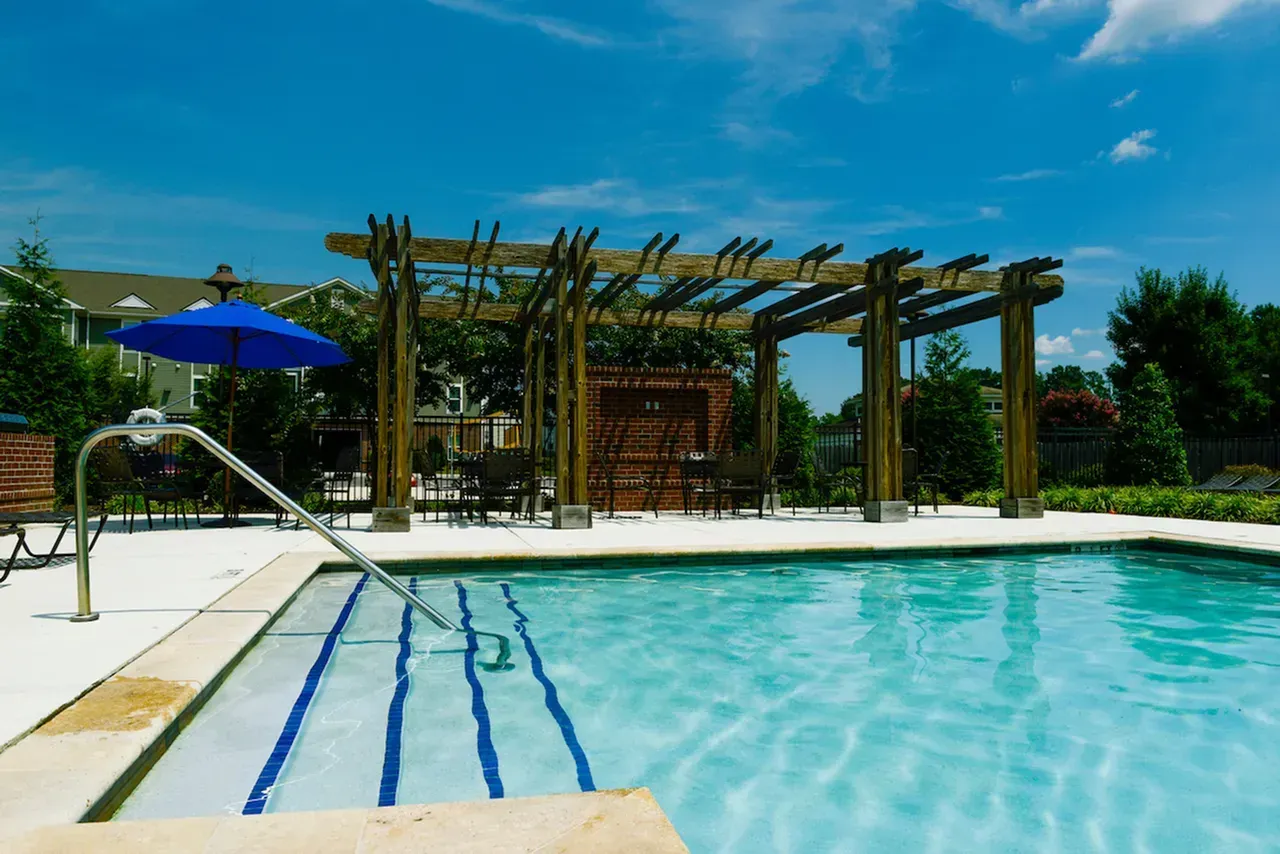 Outdoor swimming pool with blue umbrellas and a wooden pergola by the deck