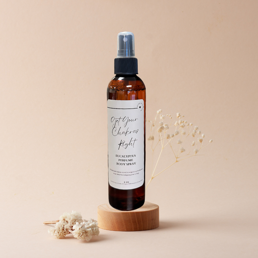 A spray bottle is sitting on a wooden block next to dried flowers.