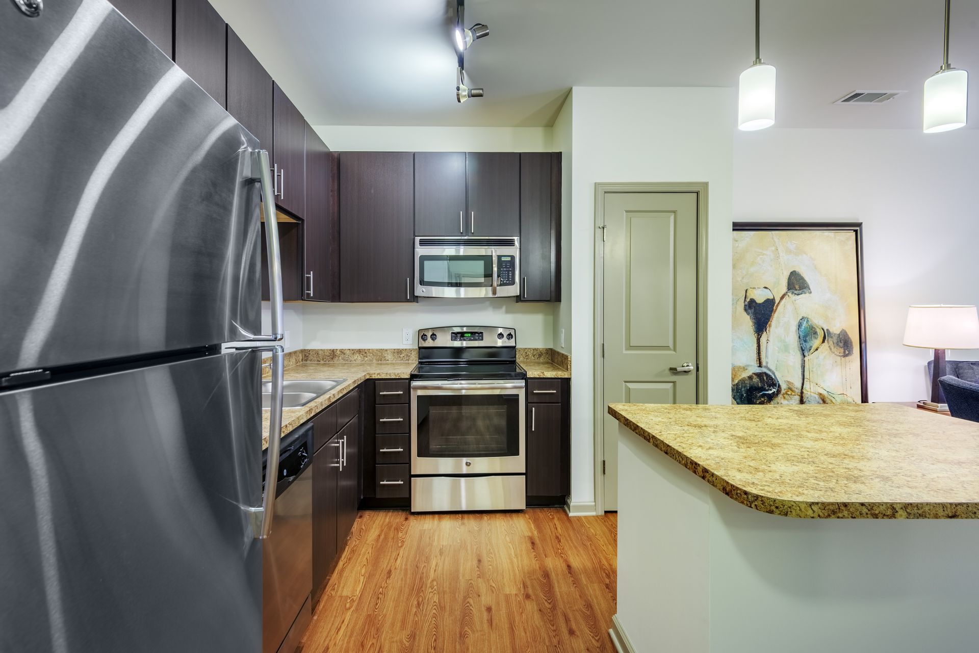 Modern kitchen with stainless steel appliances, dark cabinets, and granite countertops.