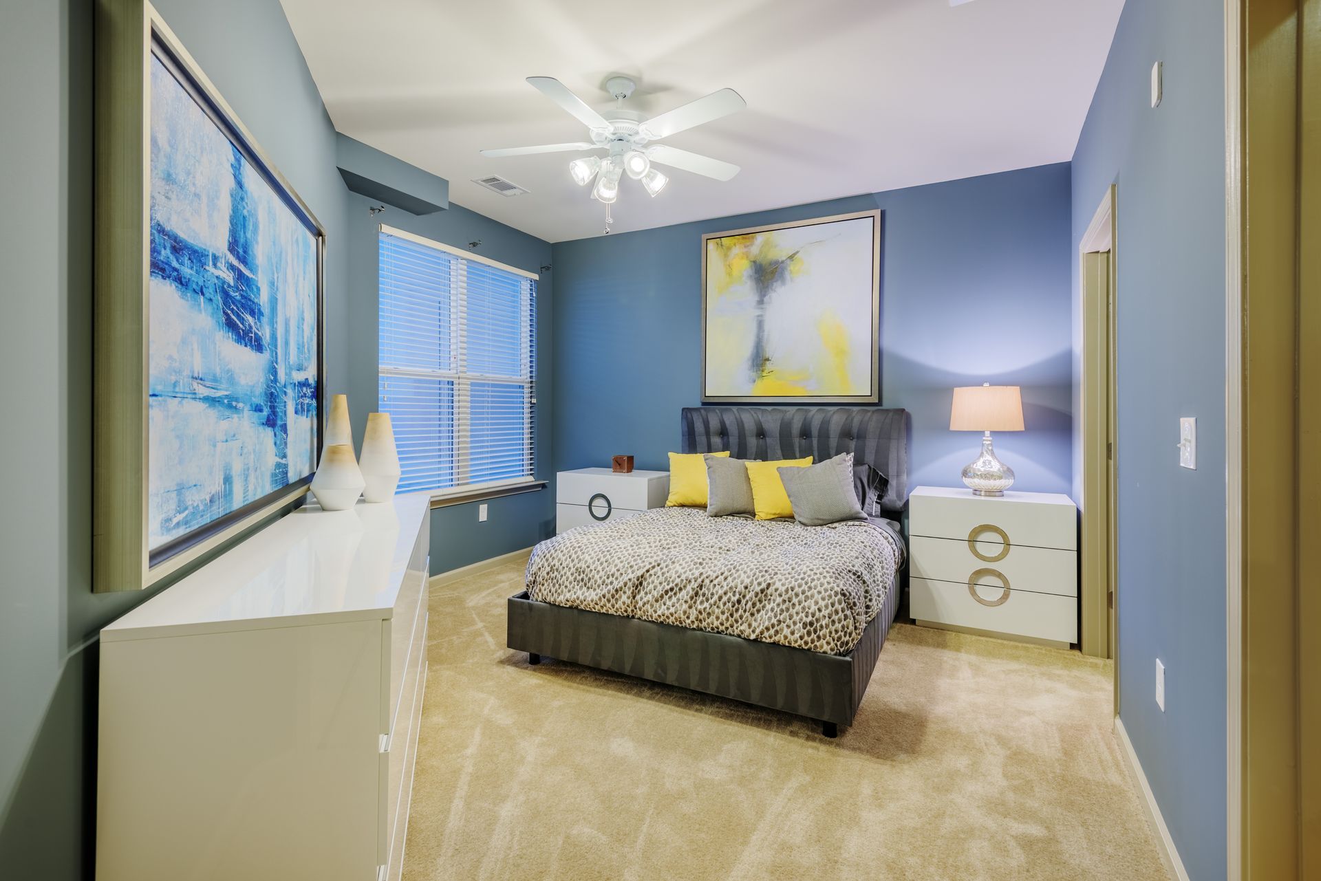 Bedroom with blue walls, double bed, white dresser, and tan carpet.